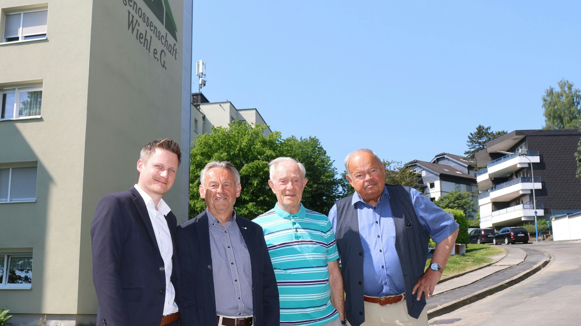 Das Bild zeigt die Führungsmitglieder der Baugenossenschaft vor einem ihrer Hochhäuser.