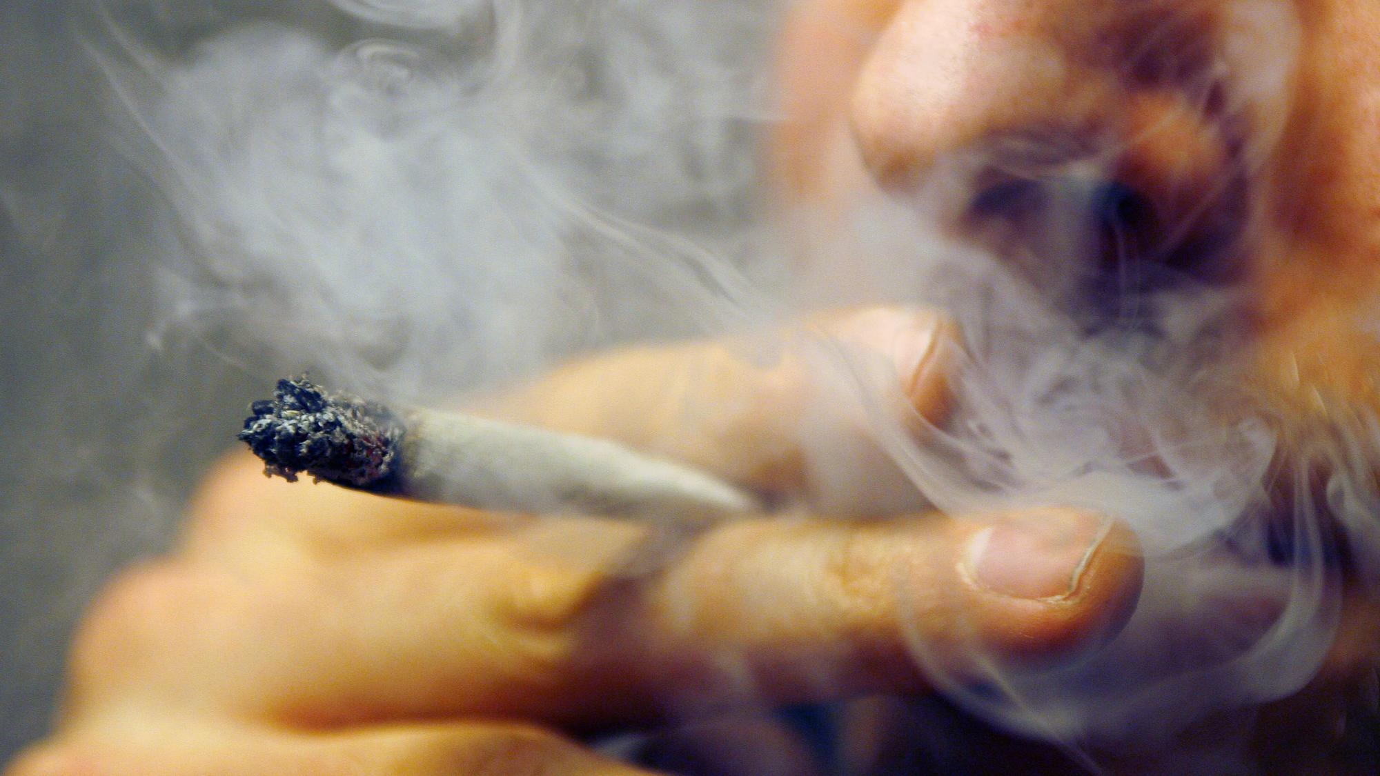 Ein Mann raucht einen Joint mit Marihuana.