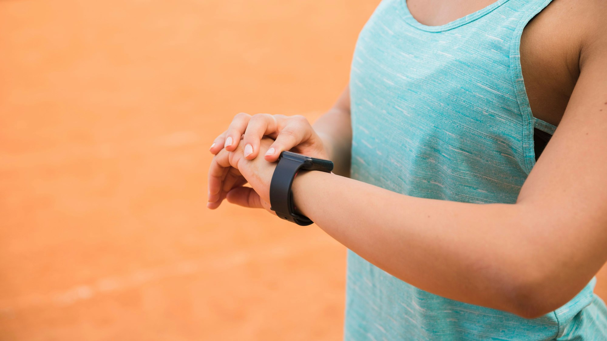 Eine Frau in Sportkleidung schaut auf ihre Fitnesstracker-Uhr.