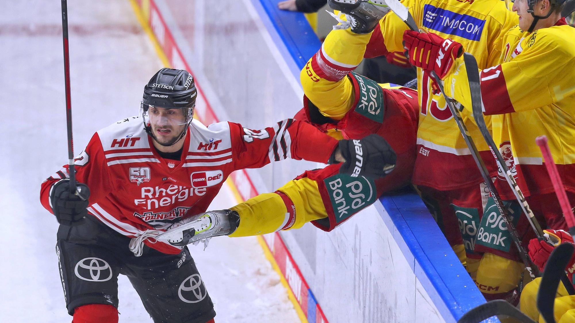 Maximilian Glötzl von Kölner Haie schickt Josef Eham von Düsseldorfer EG über die Bande vom Spielfeld auf die Spielerbank.