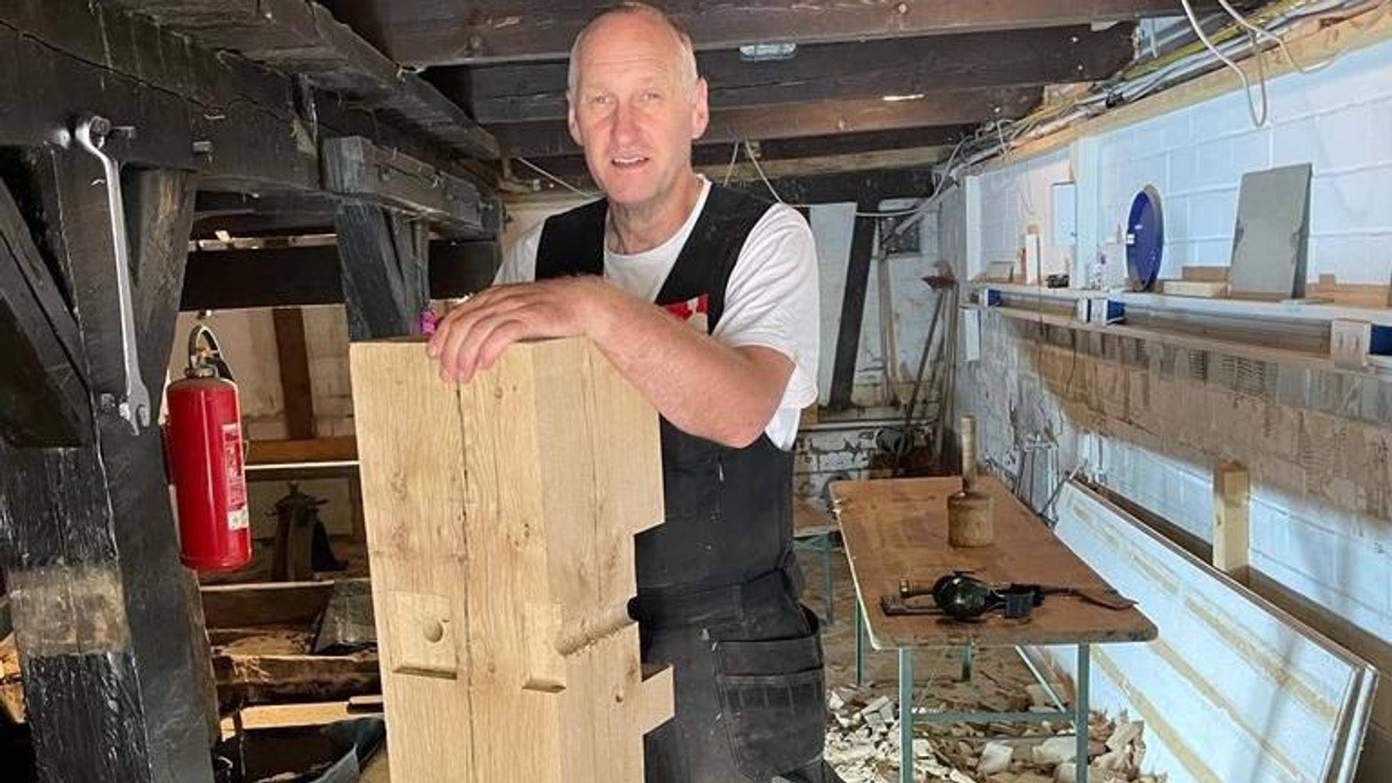 Ein Handwerker hält ein großes Holzstück.