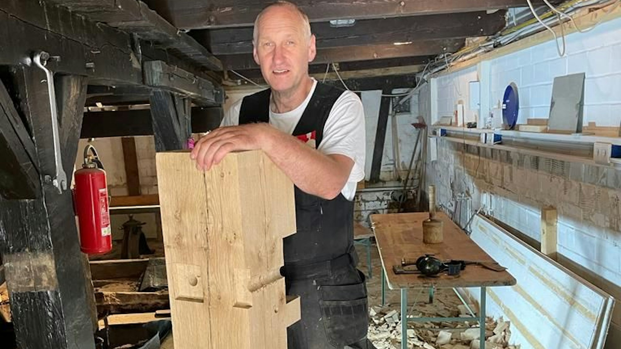 Ein Handwerker hält ein großes Holzstück.