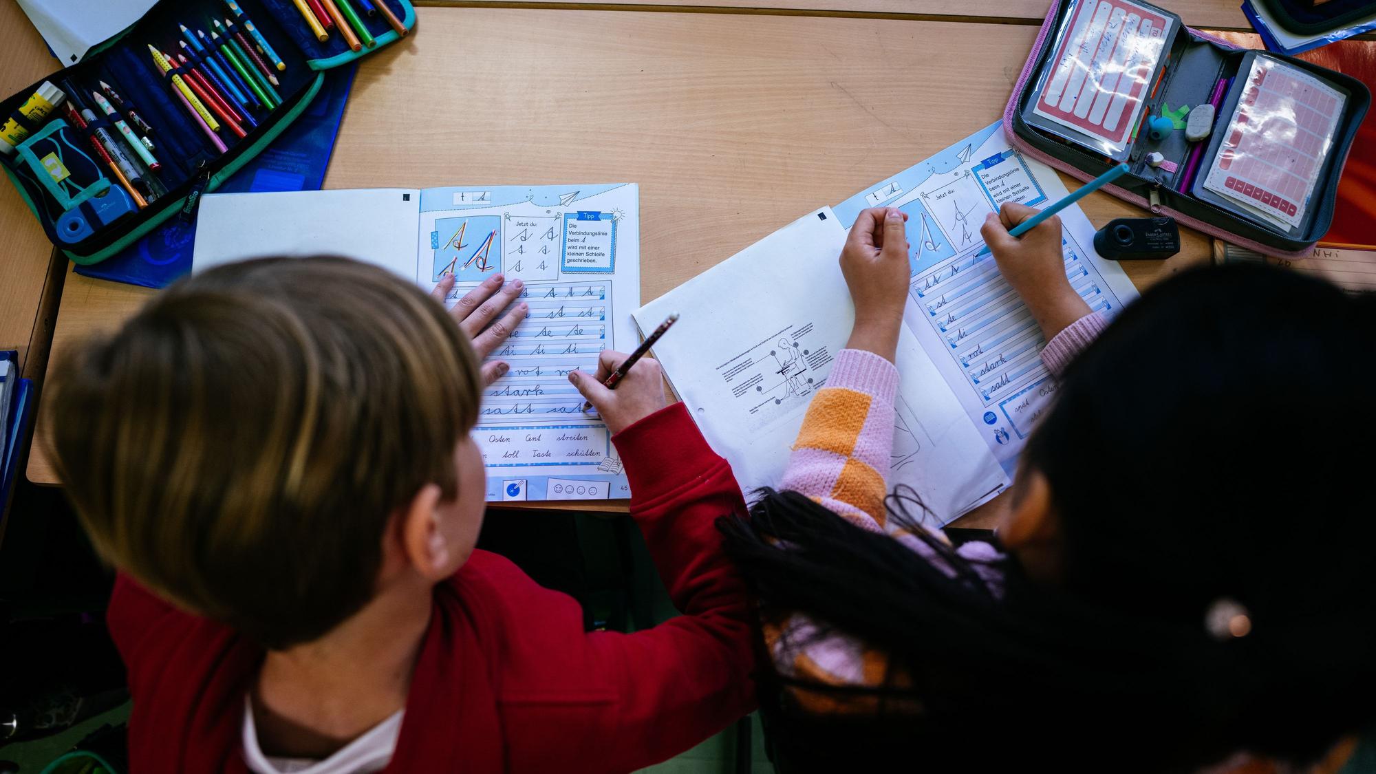 Zwei Grundschüler üben Schreibschrift.