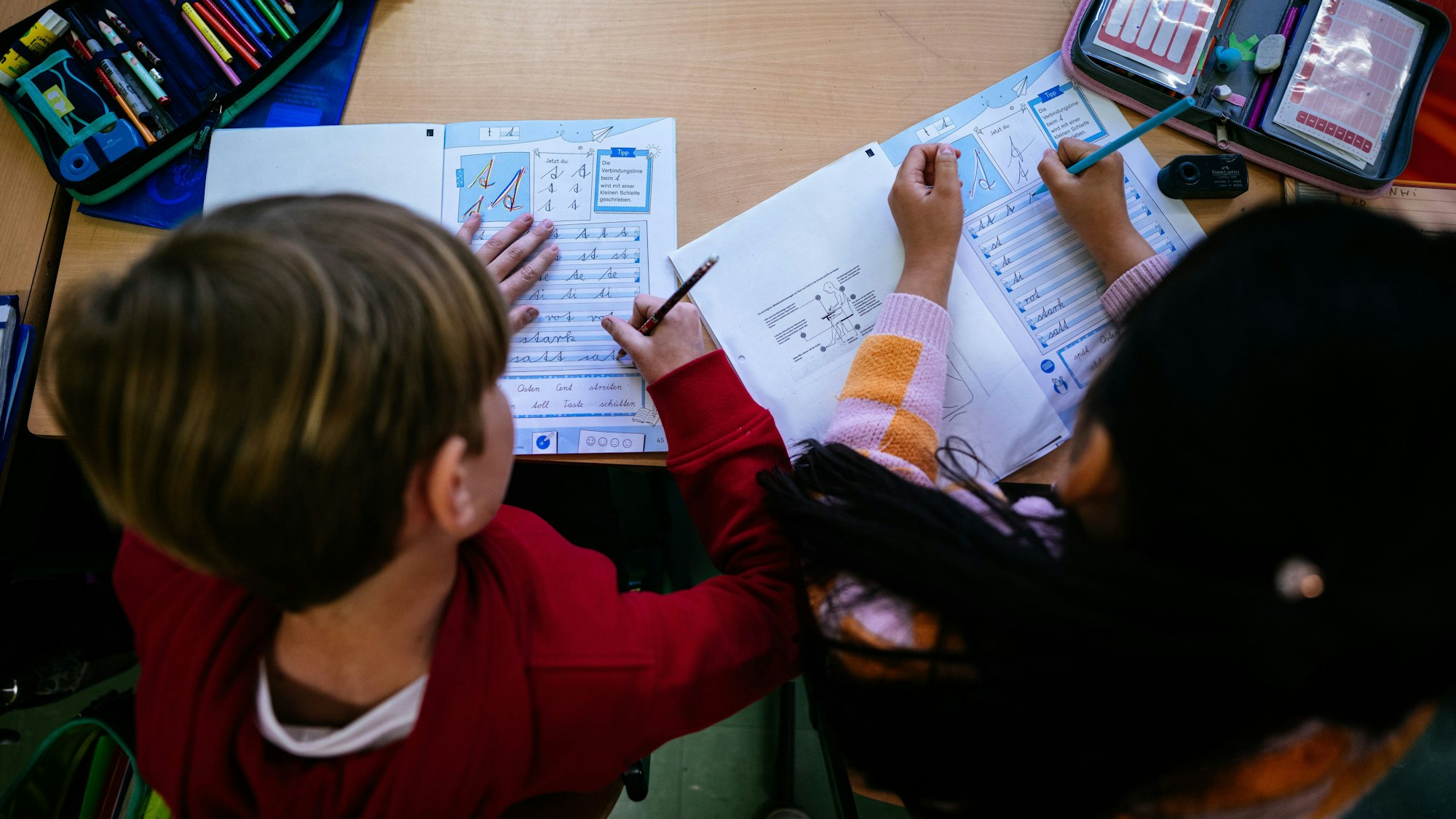 Grundschulkinder schreiben in ein Heft.