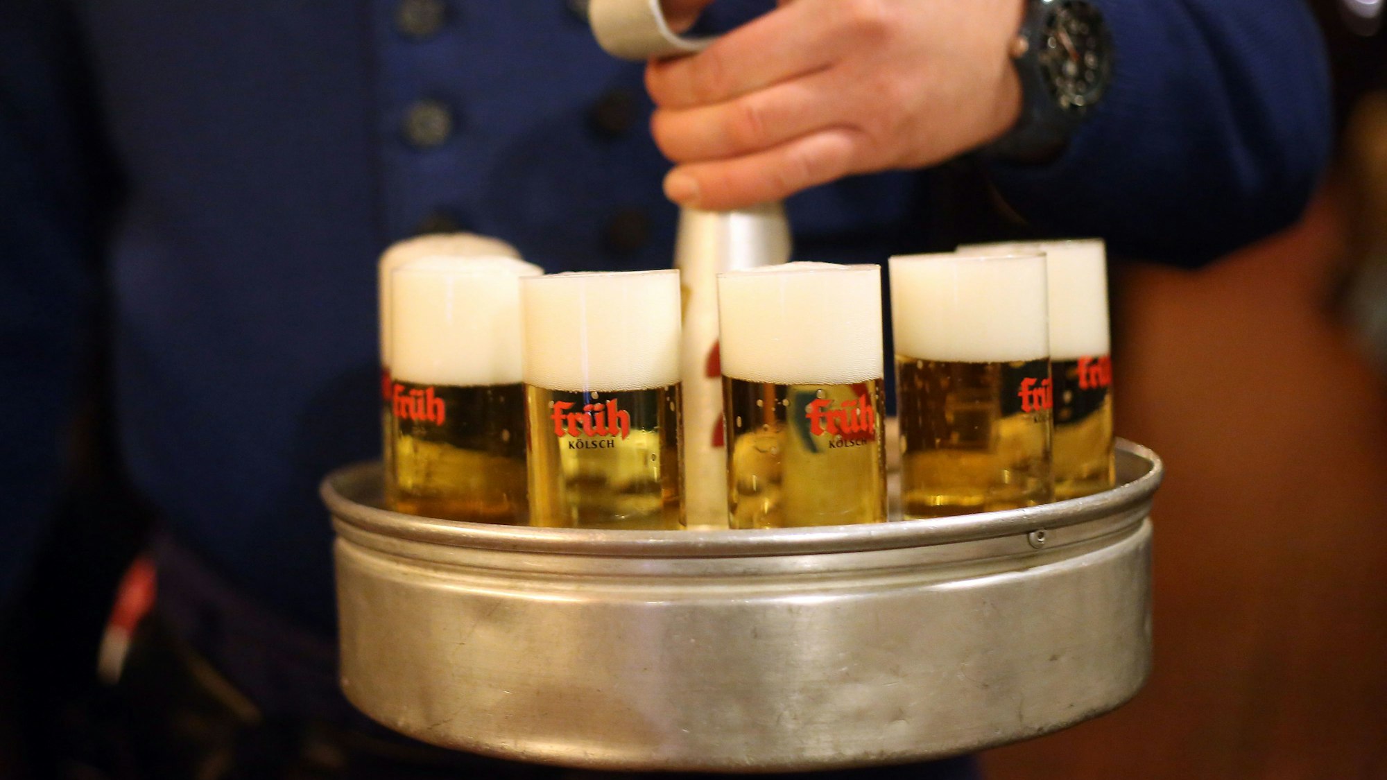 Ein Köbes trägt in Köln im Brauhaus Früh am Dom Kölsch-Bier aus.