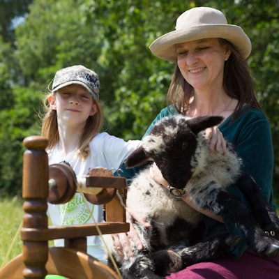 Zu sehen sind eine Mutter mit ihrem Sohn, die ein Schaf in den Armen hält.