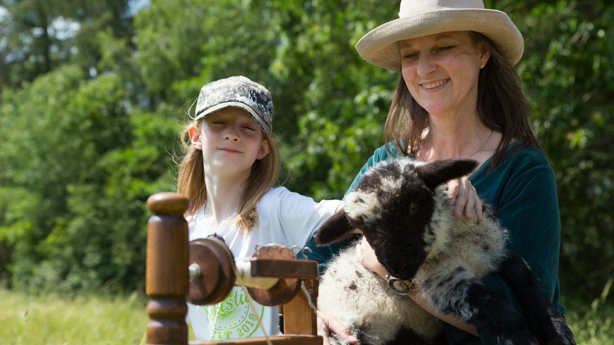 Zu sehen sind eine Mutter mit ihrem Sohn, die ein Schaf in den Armen hält.