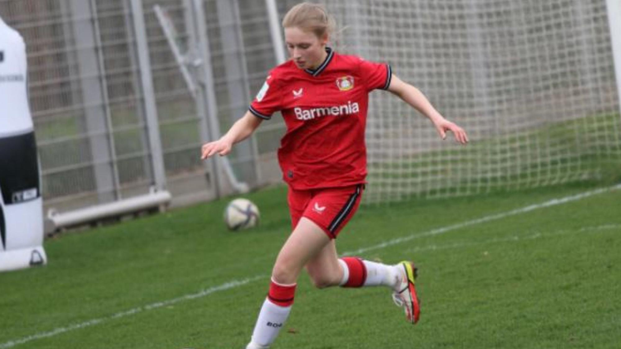 Zu sehen ist eine junge Fußballerin, die den Ball spielt.