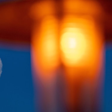 Der Mond ist am frühen Morgen neben einer Straßenlaterne am Himmel zu sehen.