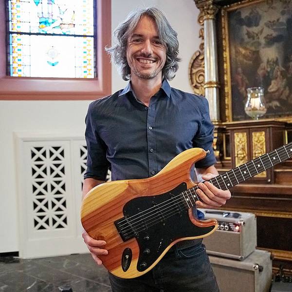 Ein Mann hält eine Gitarre in den Händen, die er aus dem Holz eines bei der Flutkatastrophe zerstörten Baums gebaut hat.