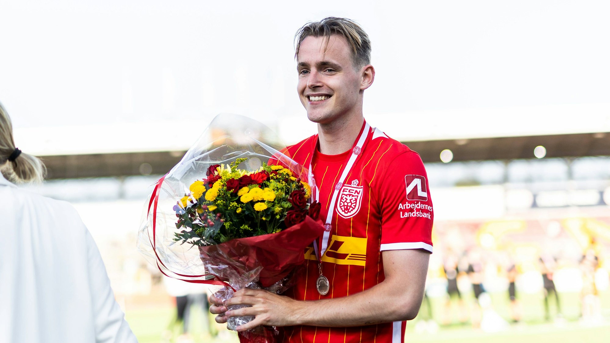 Jacob Steen Christensen steht mit einem Blumenstrauß auf dem Spielfeld.