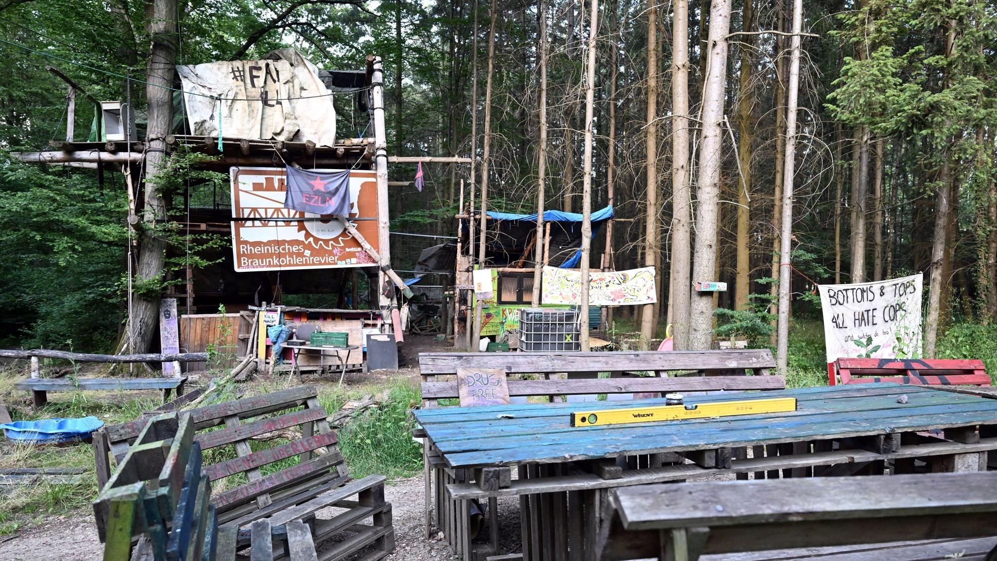 Nordrhein-Westfalen, Morschenich: Verlassene Baumhäuser stehen im Hambacher Forst hinter leeren Tischen und Bänken.