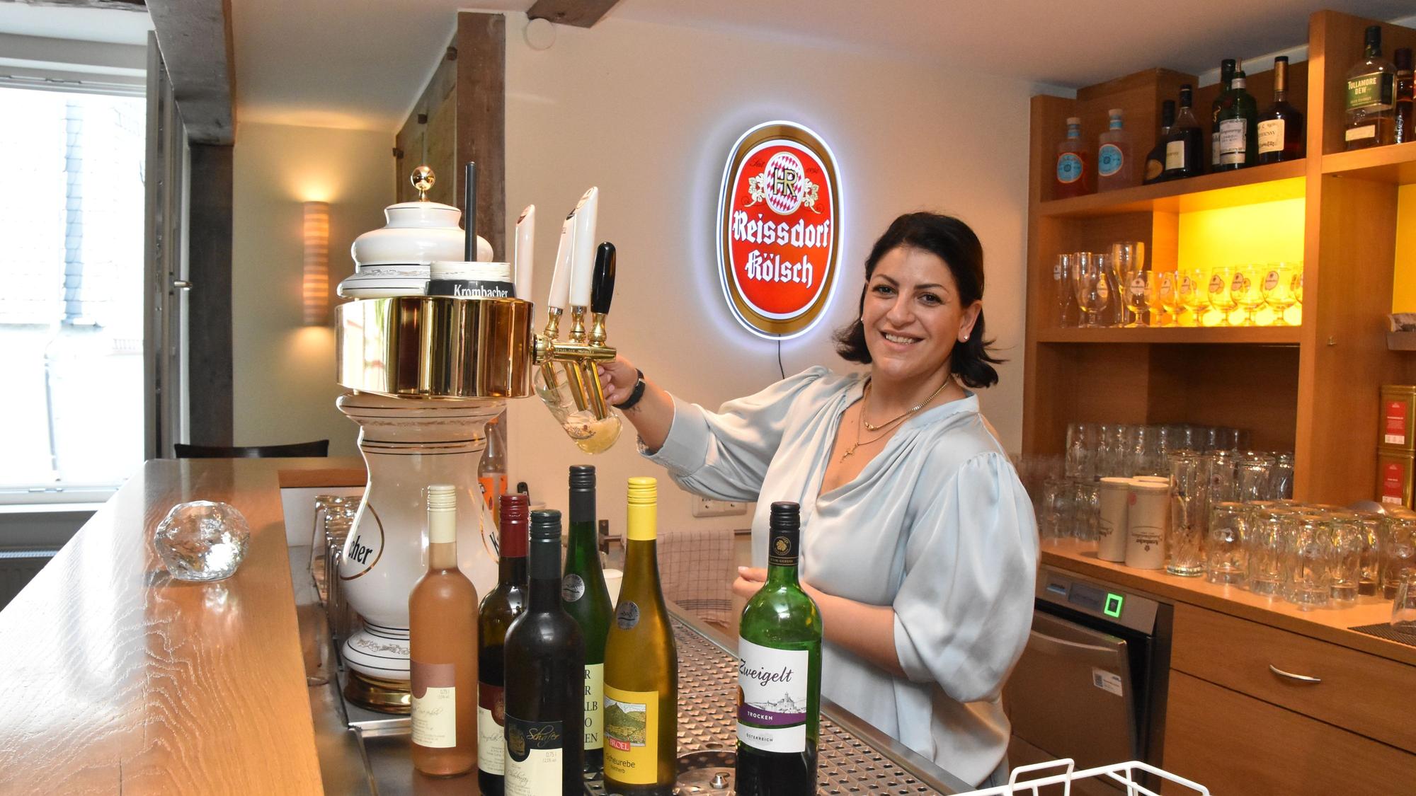 Arsine steht hinter der Theke und zapft ein Bier.