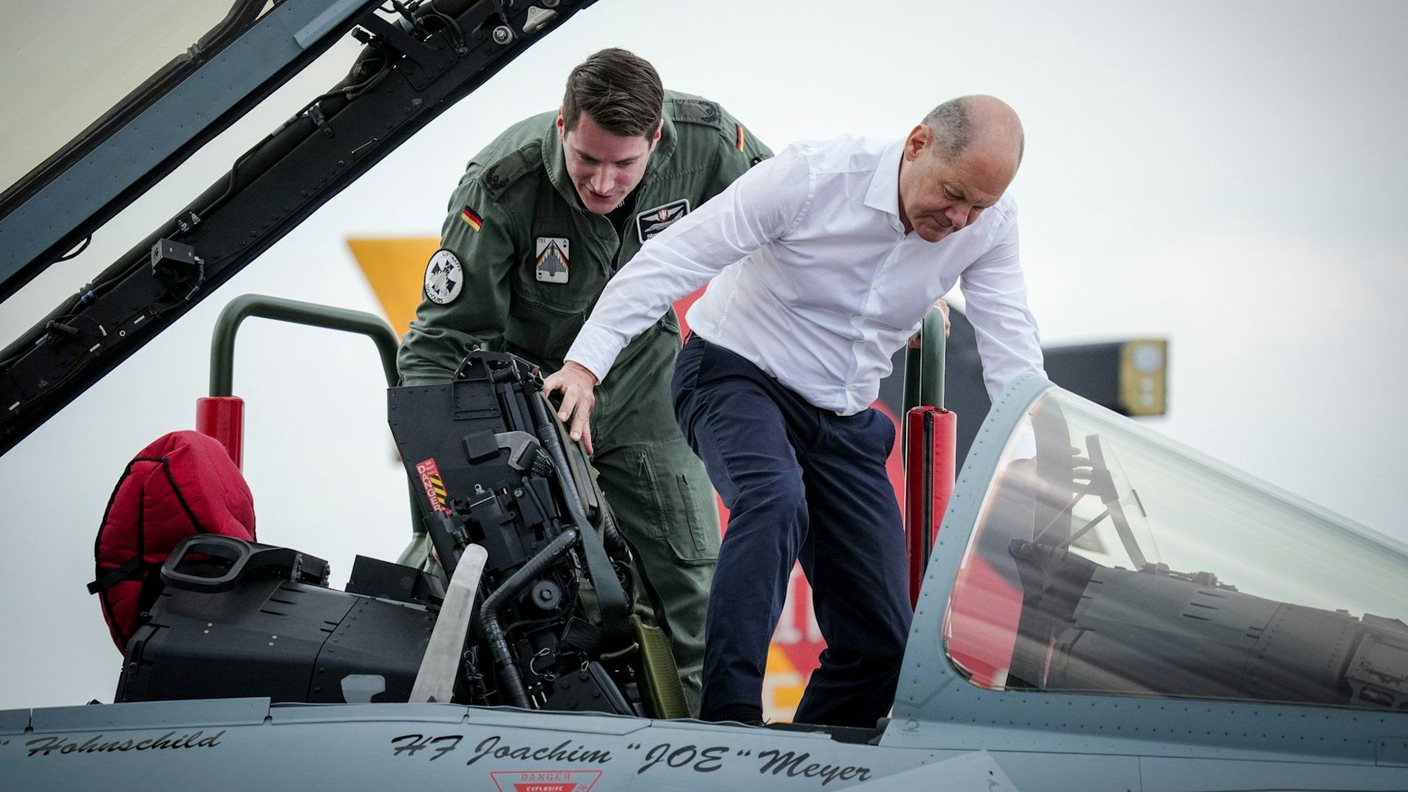 Bundeskanzler Olaf Scholz (SPD, r) steigt neben dem Piloten Steven R. in das Cockpit eines Kampfflugzeugs vom Typ Eurofighter der Luftwaffe bei seinem Besuch des internationalen Luftwaffen-Manövers «Air Defender 2023» auf dem Luftwaffenstützpunkt Jagel.