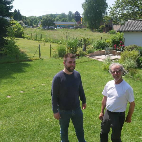 Luca Schwarzer und Ferdinand Patt stehen nebeneinander auf einer Wiese und lachen in die Kamera.