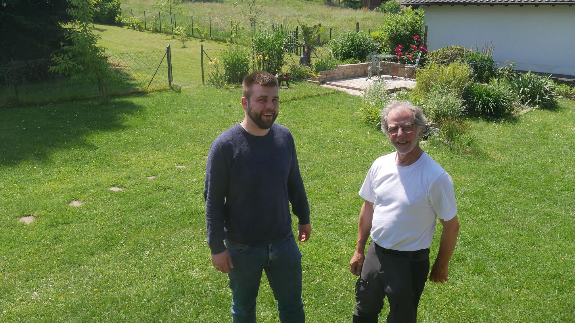 Luca Schwarzer und Ferdinand Patt stehen nebeneinander auf einer Wiese und lachen in die Kamera.