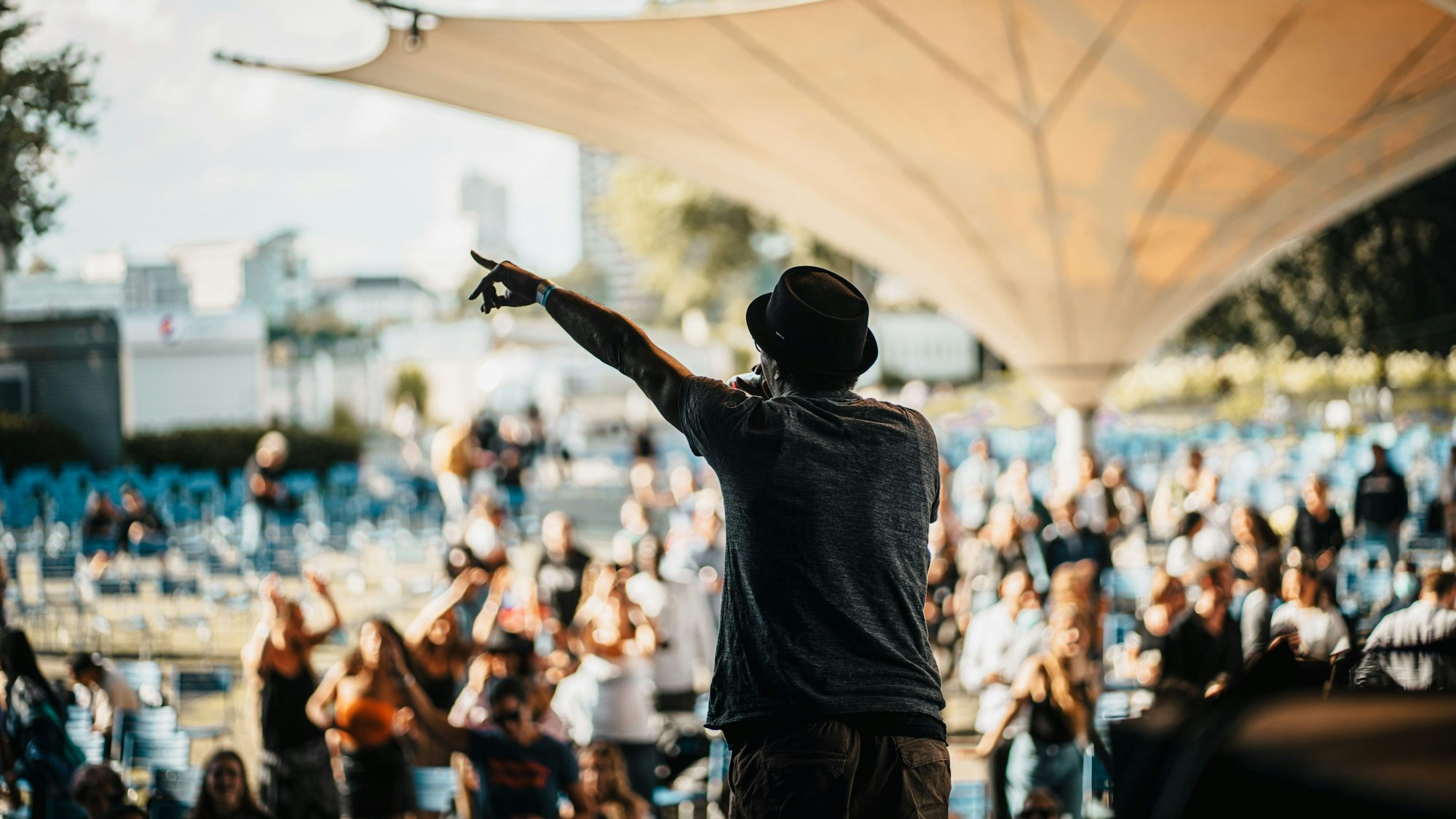 Ein Mann steht am Tanzbrunnen auf der Bühne, vor ihm stehen viele Menschen.