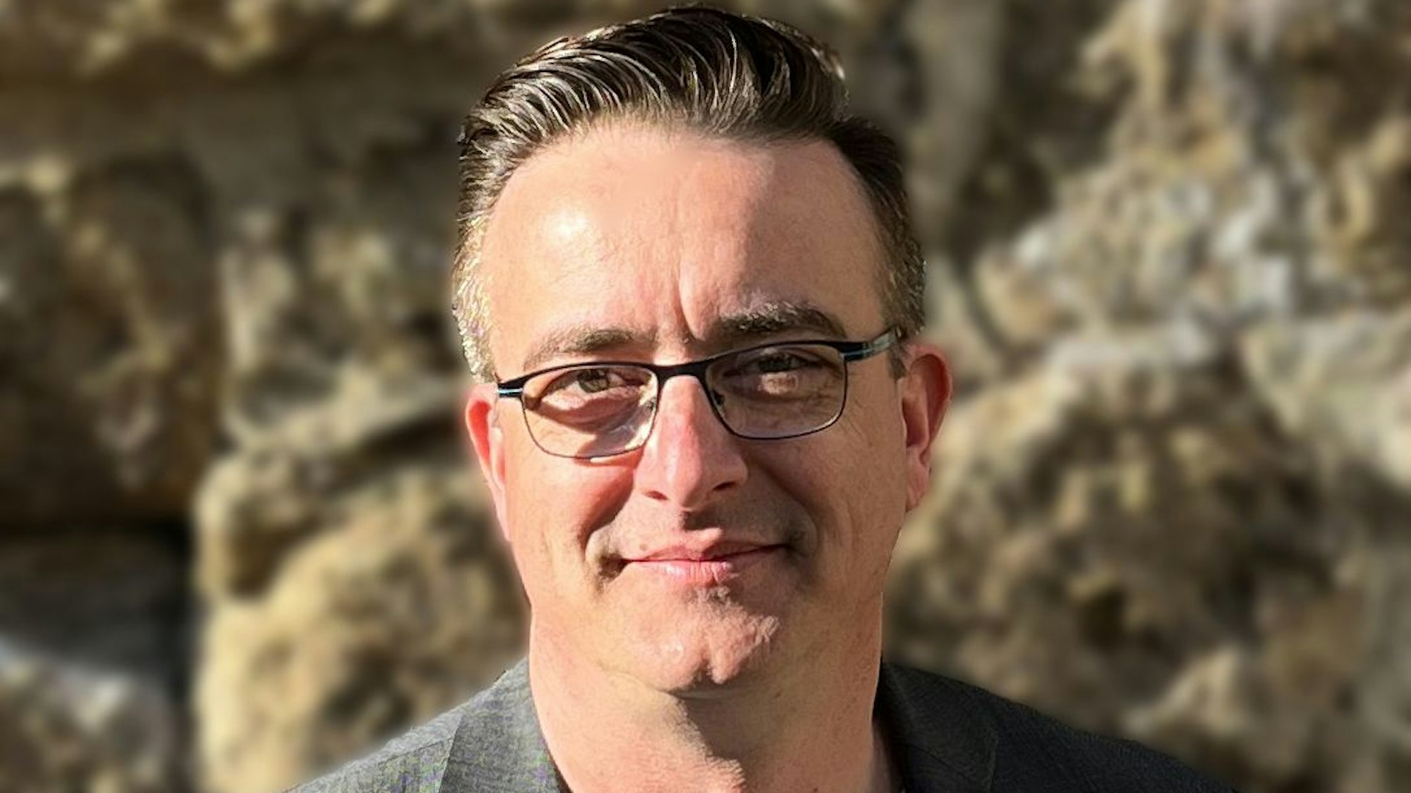 Ein Mann steht vor einer Mauer im Sonnenschein.