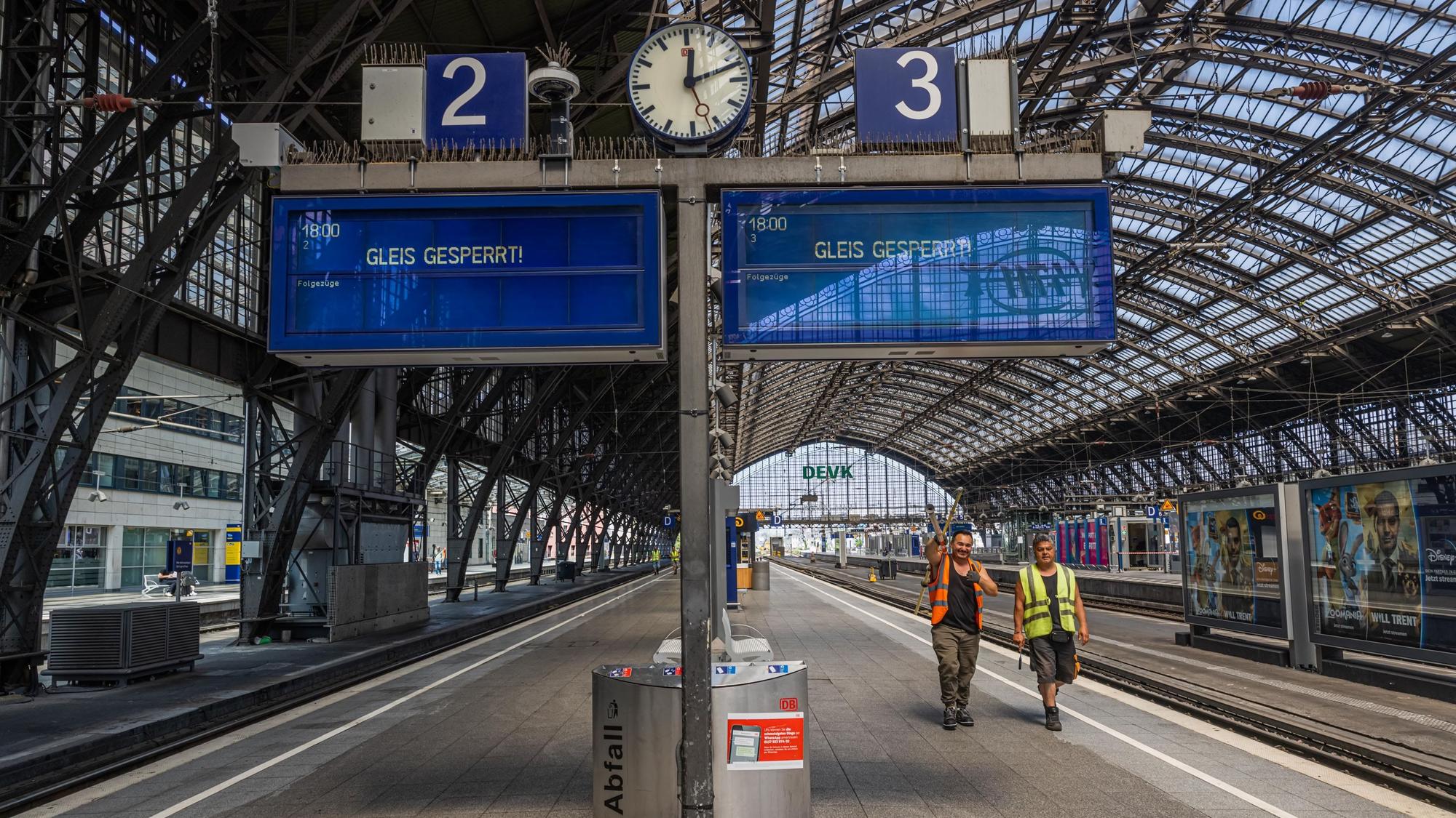 Zwei Bauarbeiter sind am gesperrten Gleis drei unterwegs.