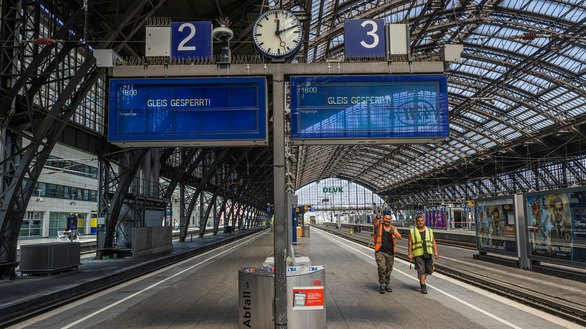 Zwei Bauarbeiter sind am gesperrten Gleis drei unterwegs.