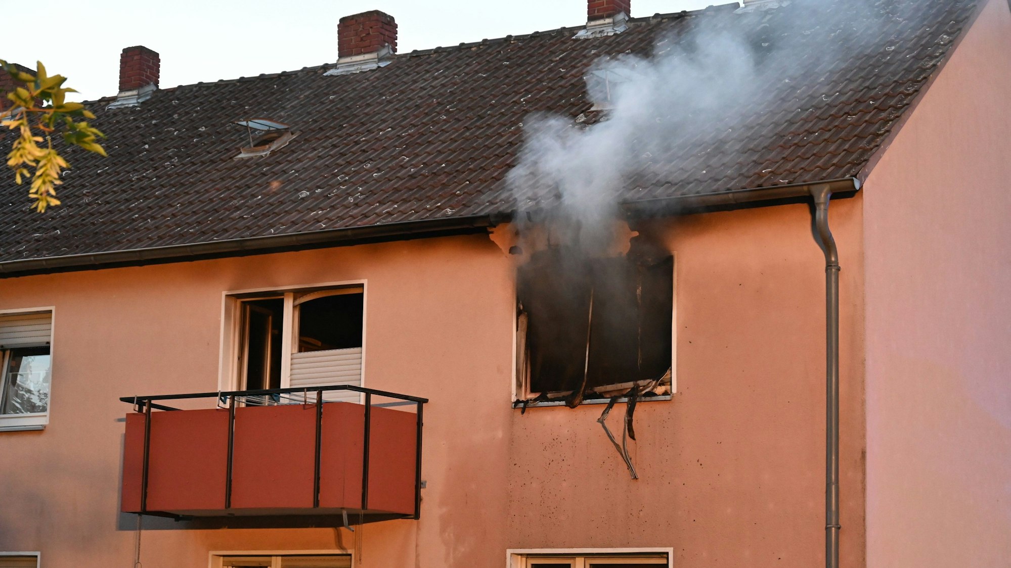 Rauch steigt aus dem Fenster eines Mehrfamilienhaues empor.