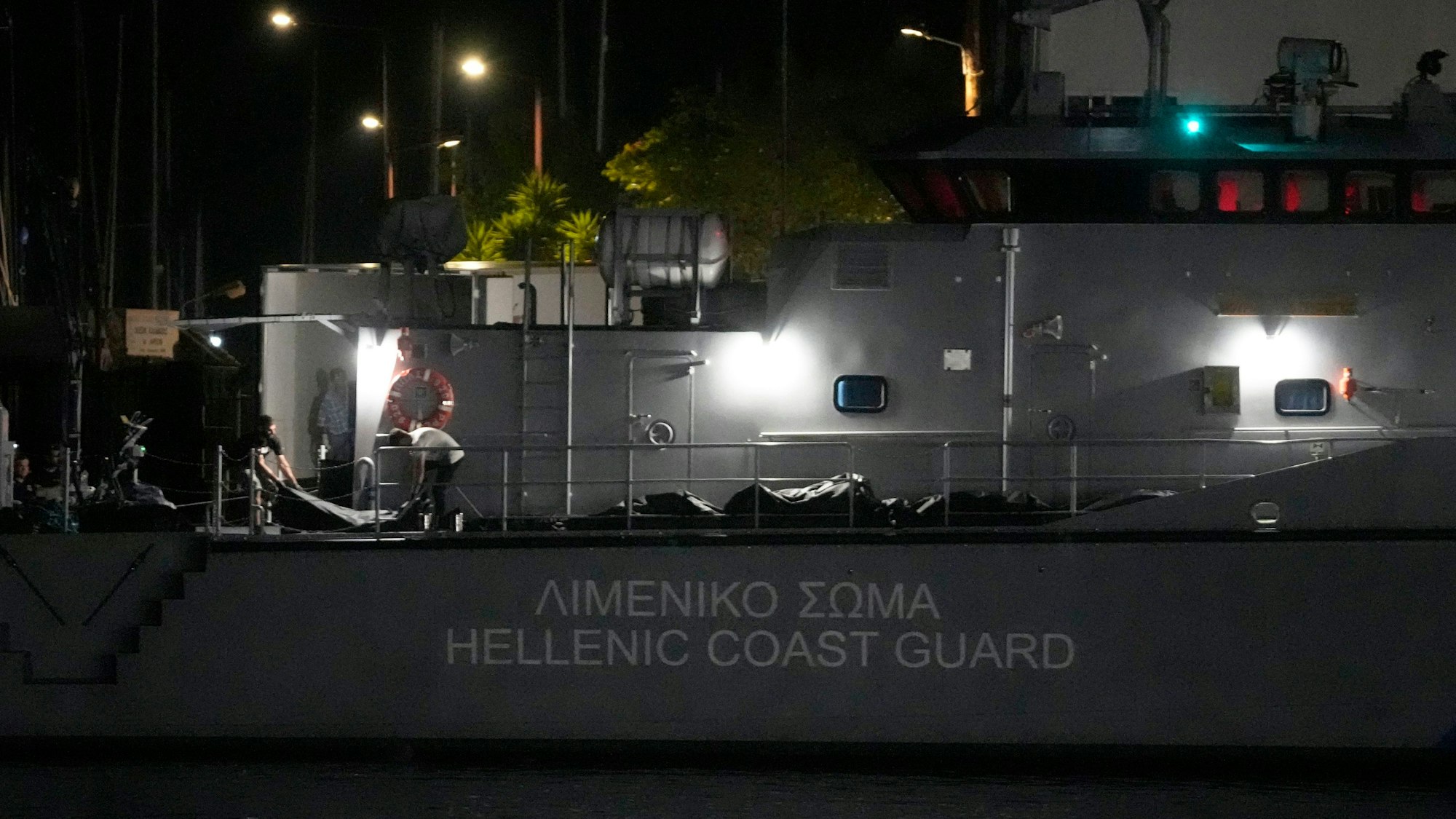 Rettungskräfte tragen Leichen von einem Schiff der Küstenwache in einen Kühlwagen im Hafen von Kalamata.