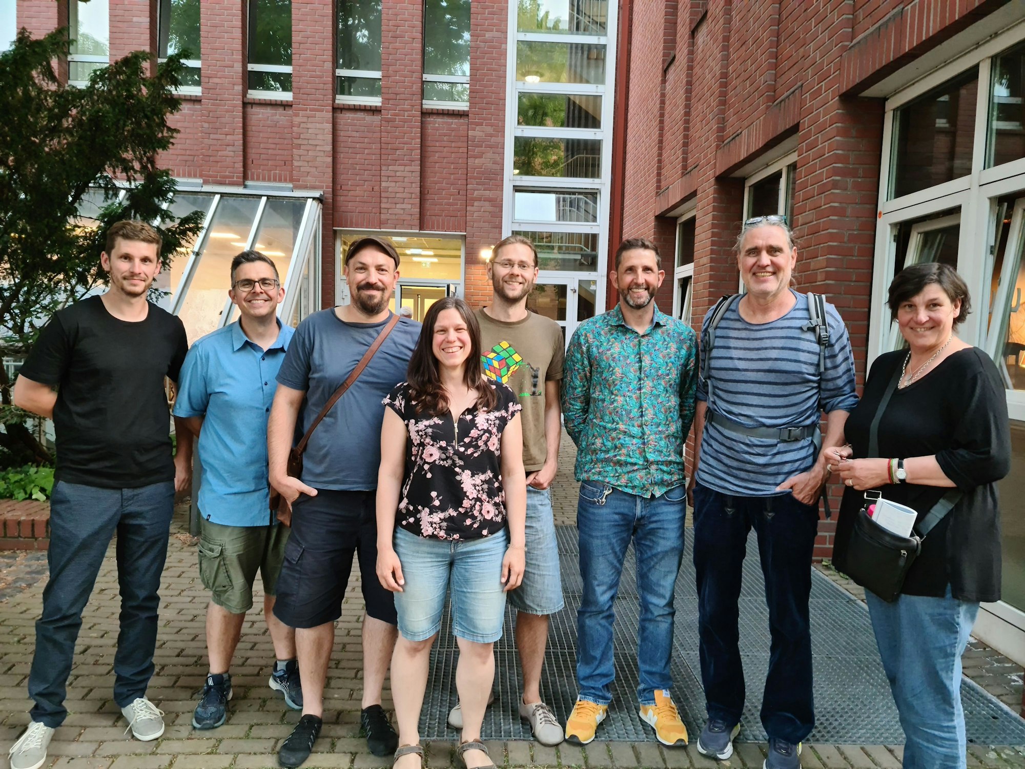 Sechs Männer und zwei Frauen stehen nebeneinander und schauen optimistisch in die Kamera.