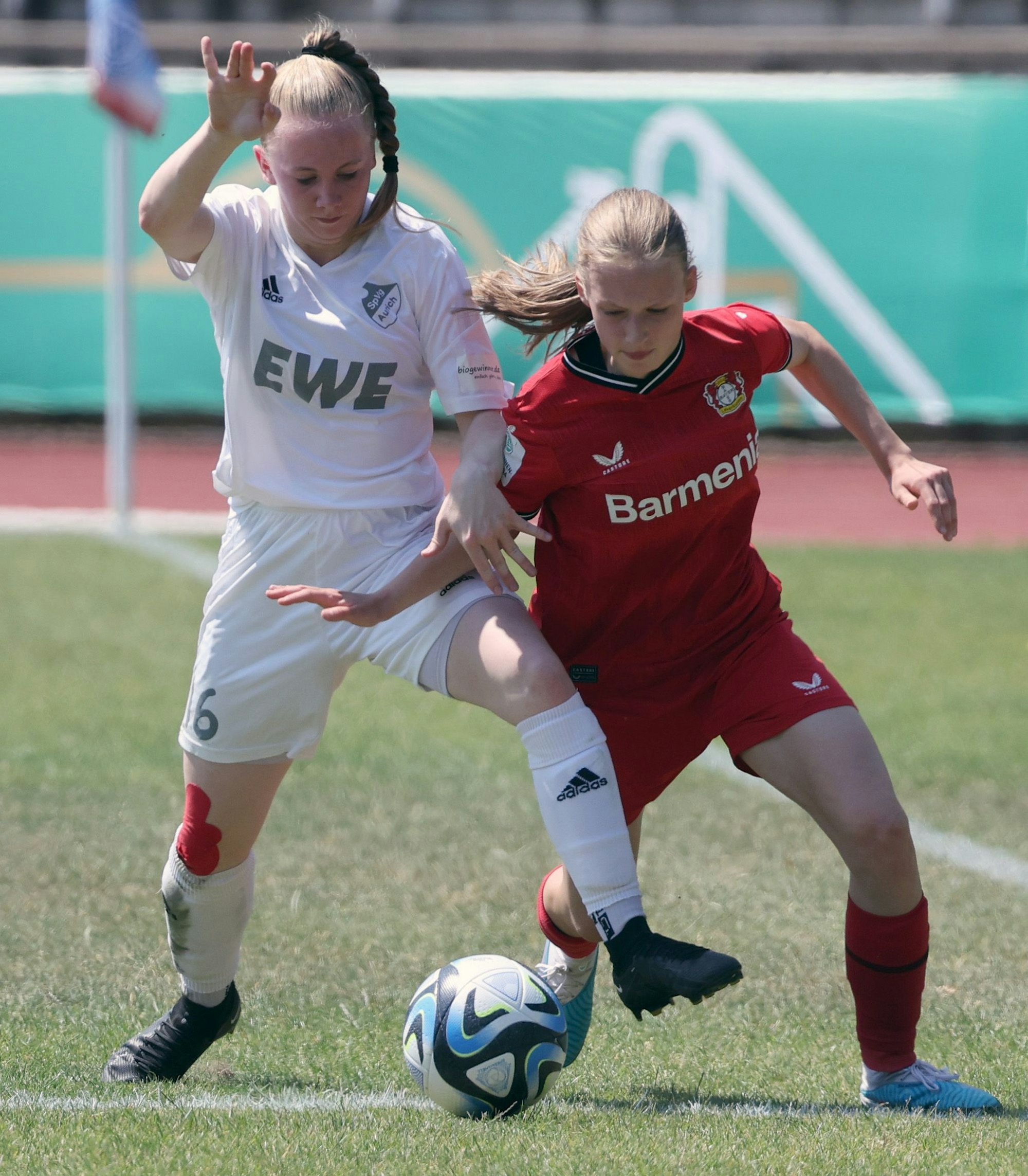 ZU sehen ist ein Zweikampf zwischen zwei jungen Fußballspielerinnen.