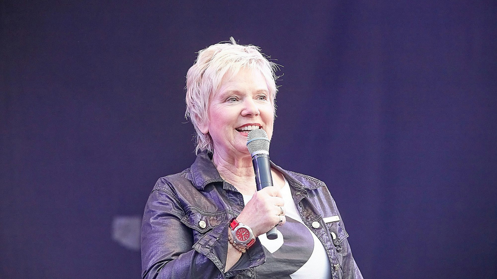 Die Moderatorin Birgit Lechtermann steht auf der Bühne und hält ein Mikrofon in der Hand.