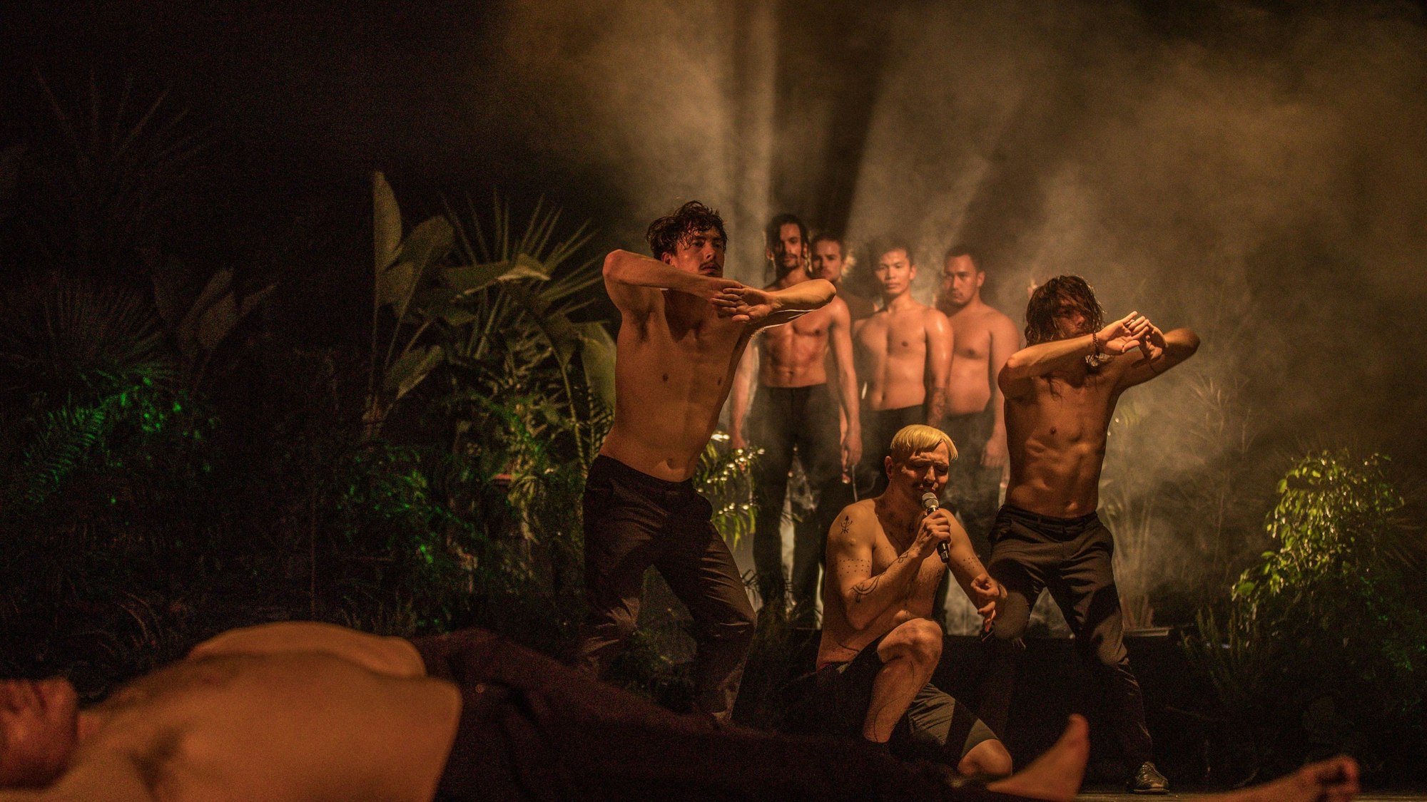 Szene aus dem Tanzgastspiel "King" von Shaun Parker & Company. Darin ist zu sehen, wie eine Gruppe Männer oberkörperfrei in einem Dschungel steht.