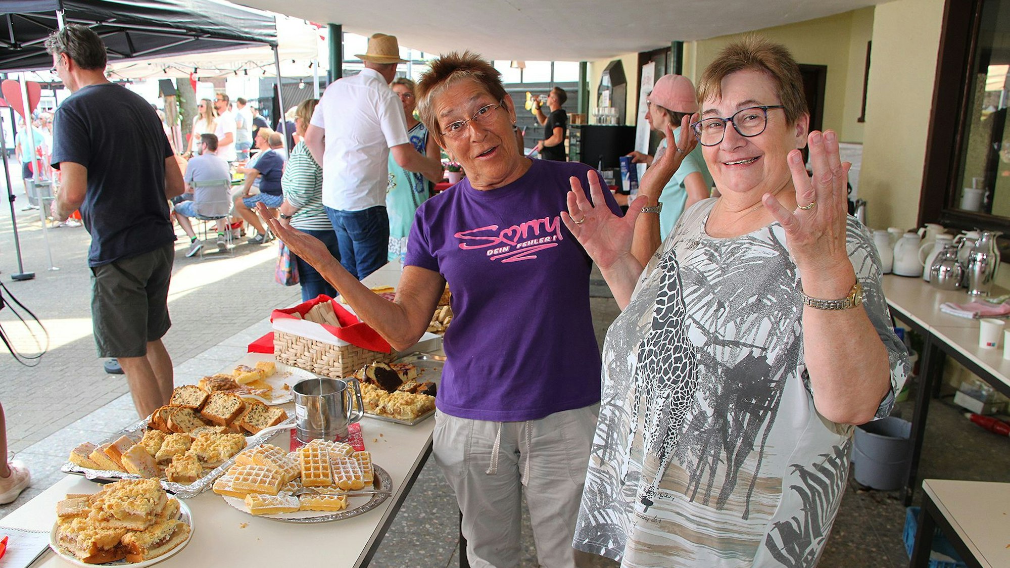 Zwei Frauen stehen vor einem Tisch mit Gebäck und Kuchen.