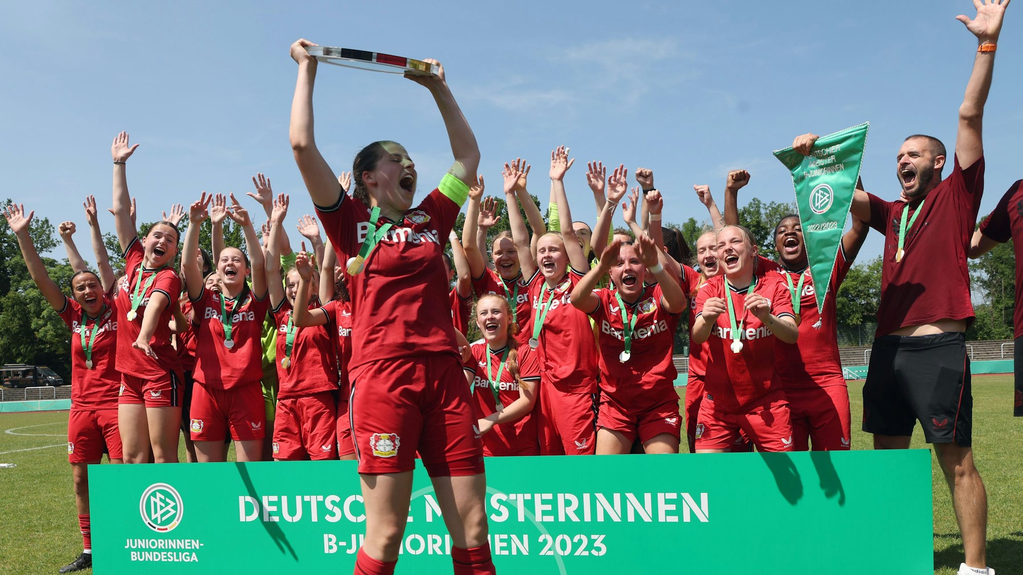 Zu sehen ist eine Mädchenmannschaft, die einen Pokal in die Höhe stemmt und feiert.