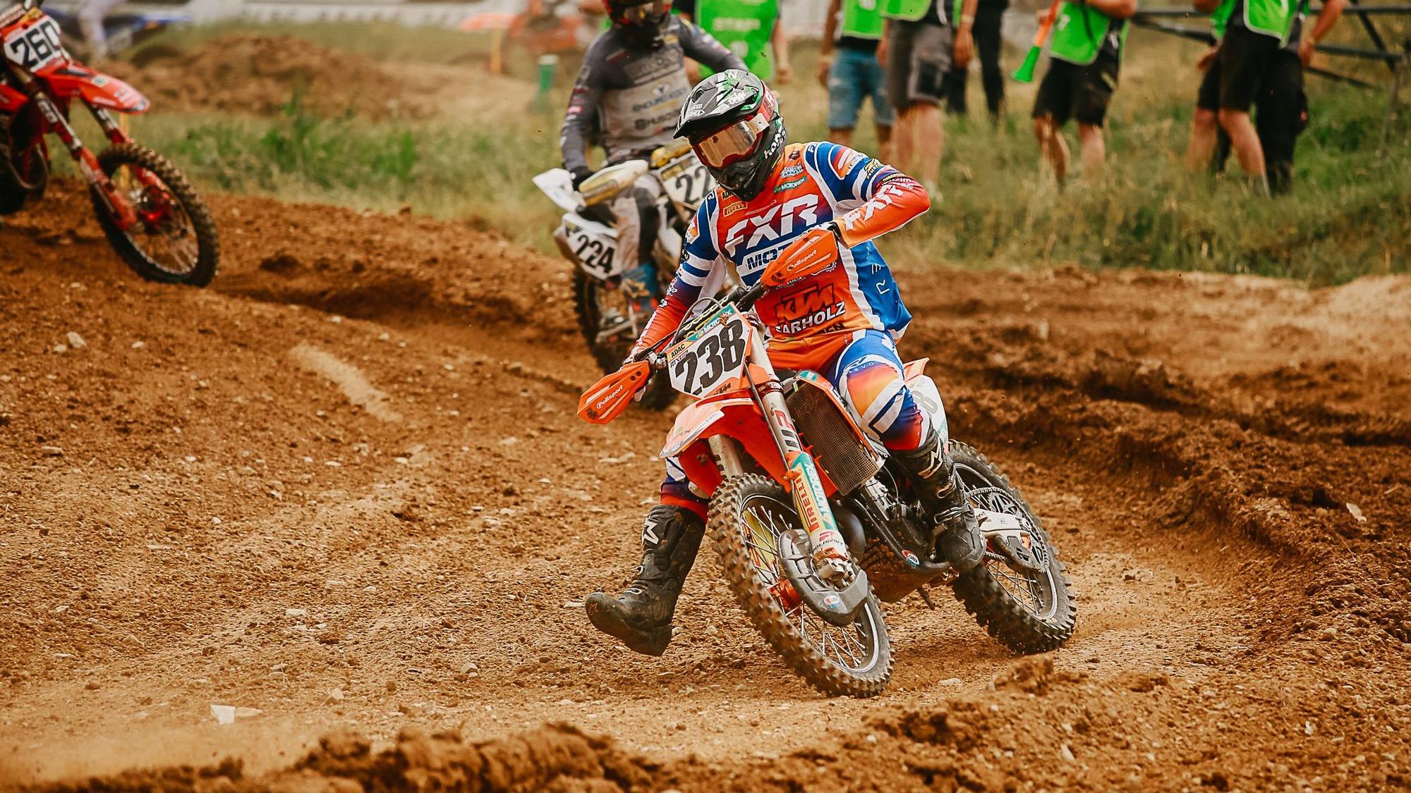 Ein Motocross-Fahrer fährt auf lehmigen Boden.