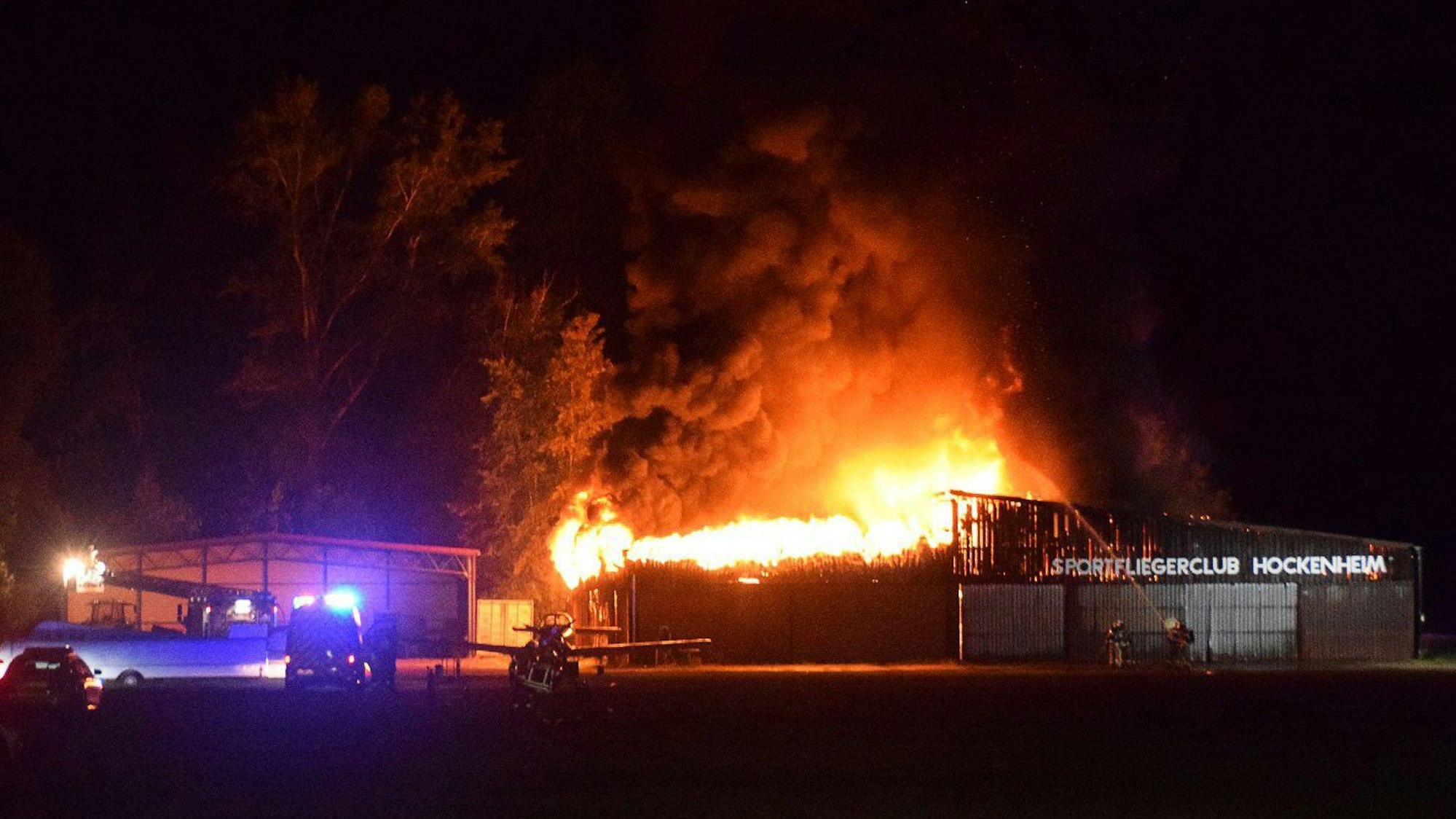 Einsatzkräfte der Feuerwehr löschen den Brand einer Lagerhalle am Flugplatz.