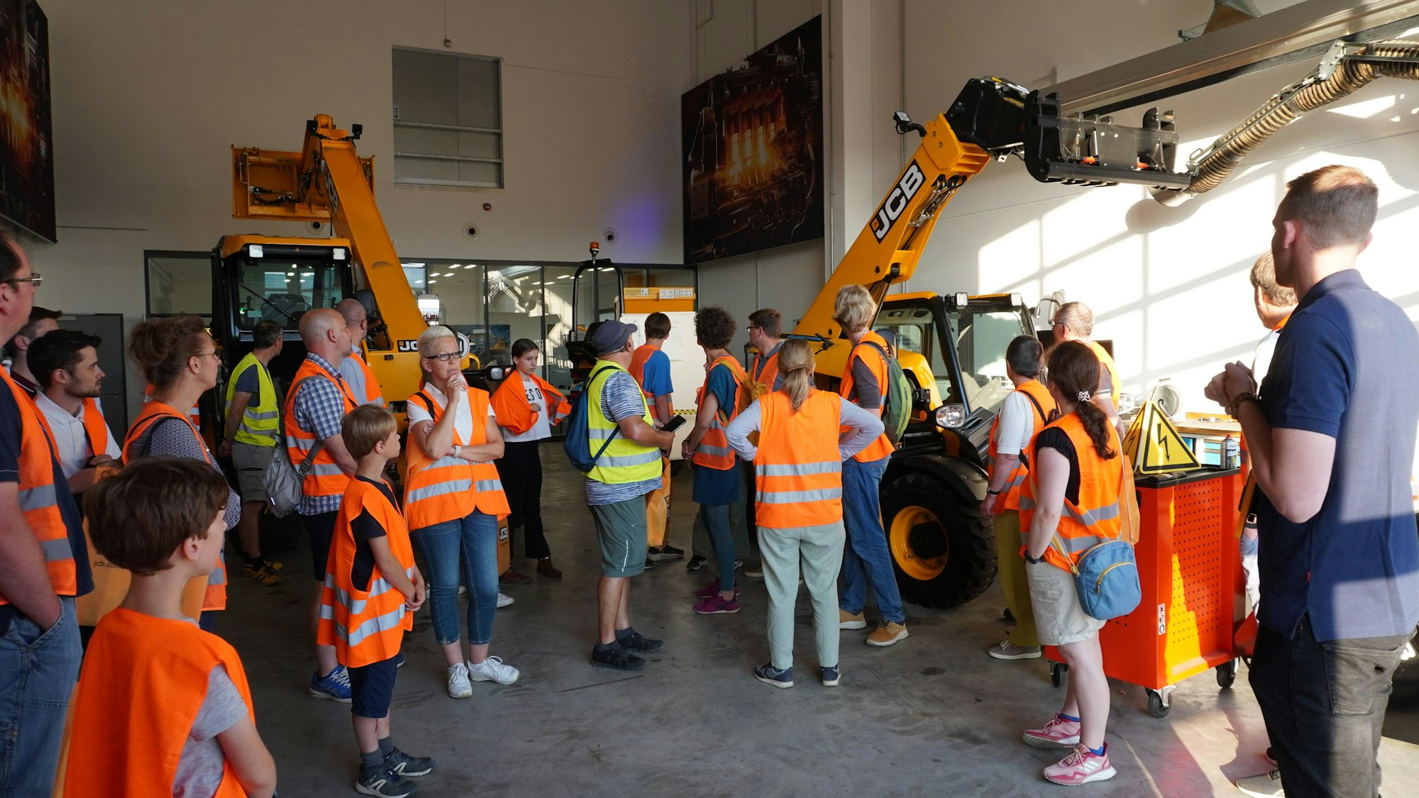 Viele Interessierte in orangen Westen nehmen an einer Führung durch das JBC-Gebäude teil.