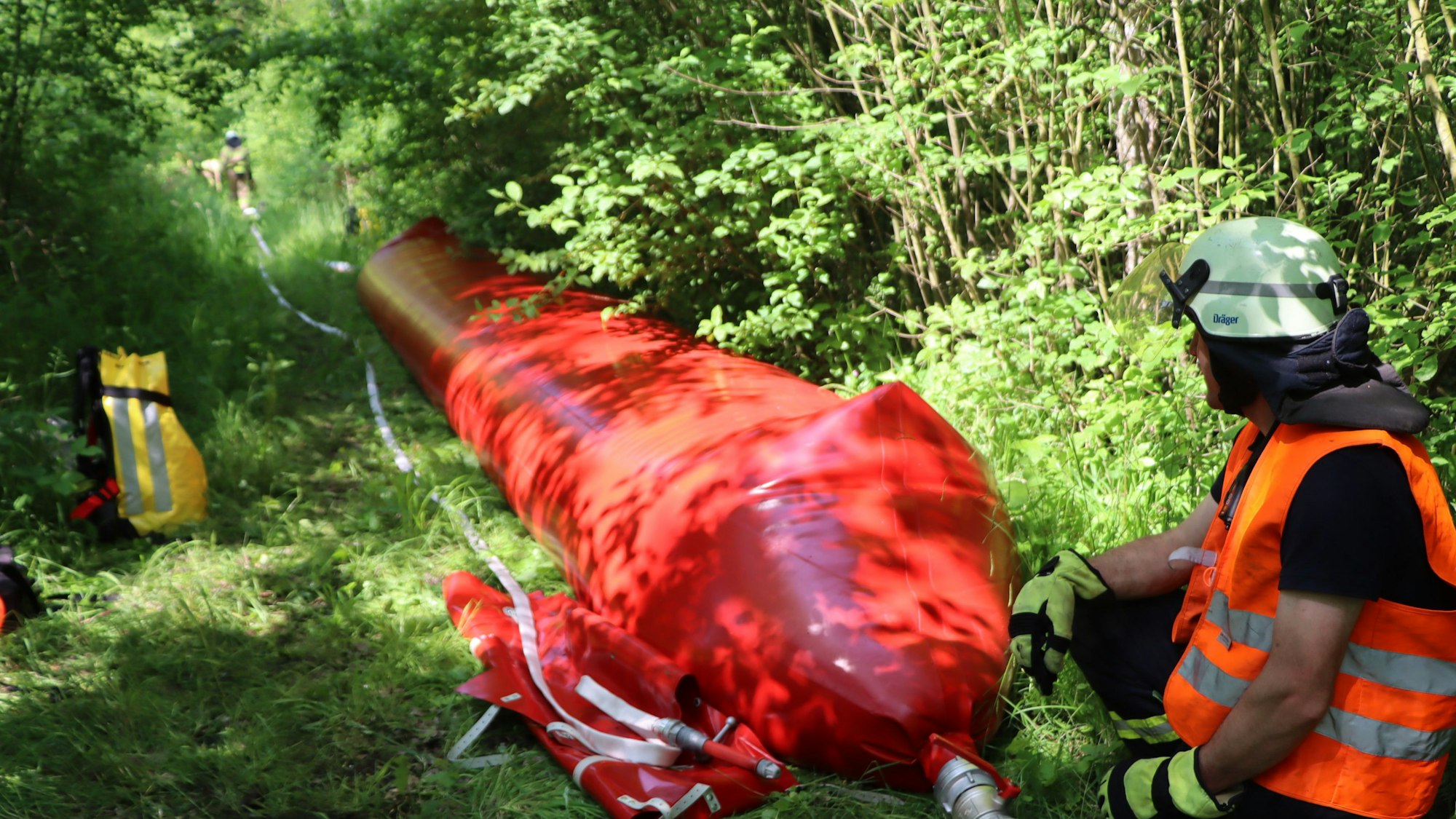 Ein Feuerwehrmann löscht ein Feuer mit einem Wassersack.
