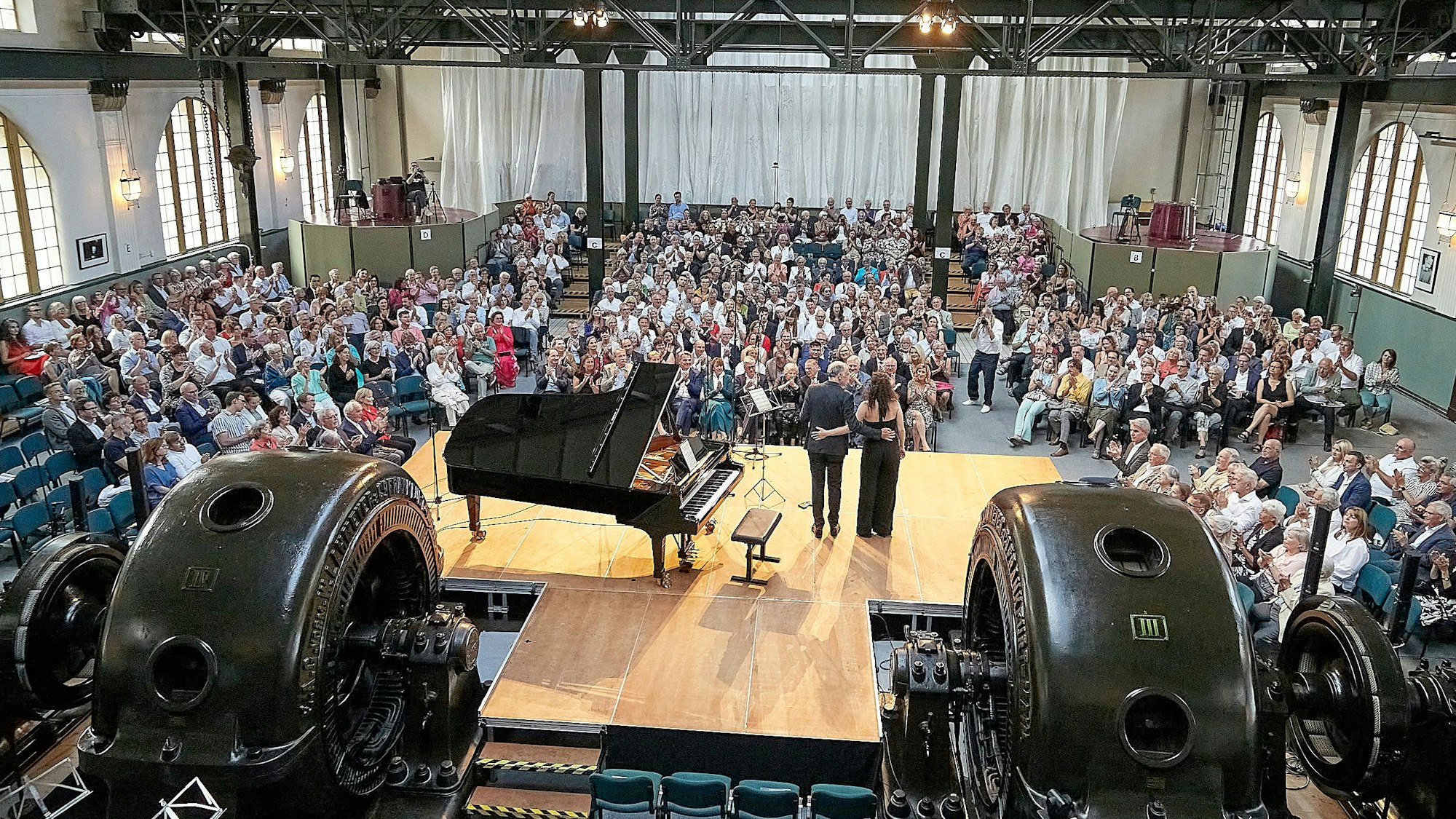 Das Bild zeigt eine Totale der Veranstaltungshalle mit Künstlern und Publikum in Heimbach.
