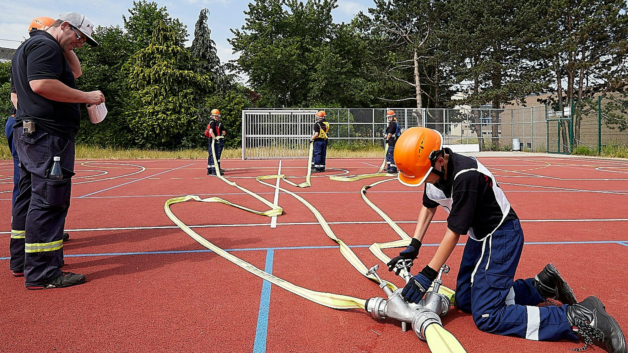 Junge Feuerwehrleute machen einen Schlauch einsatzbereit.