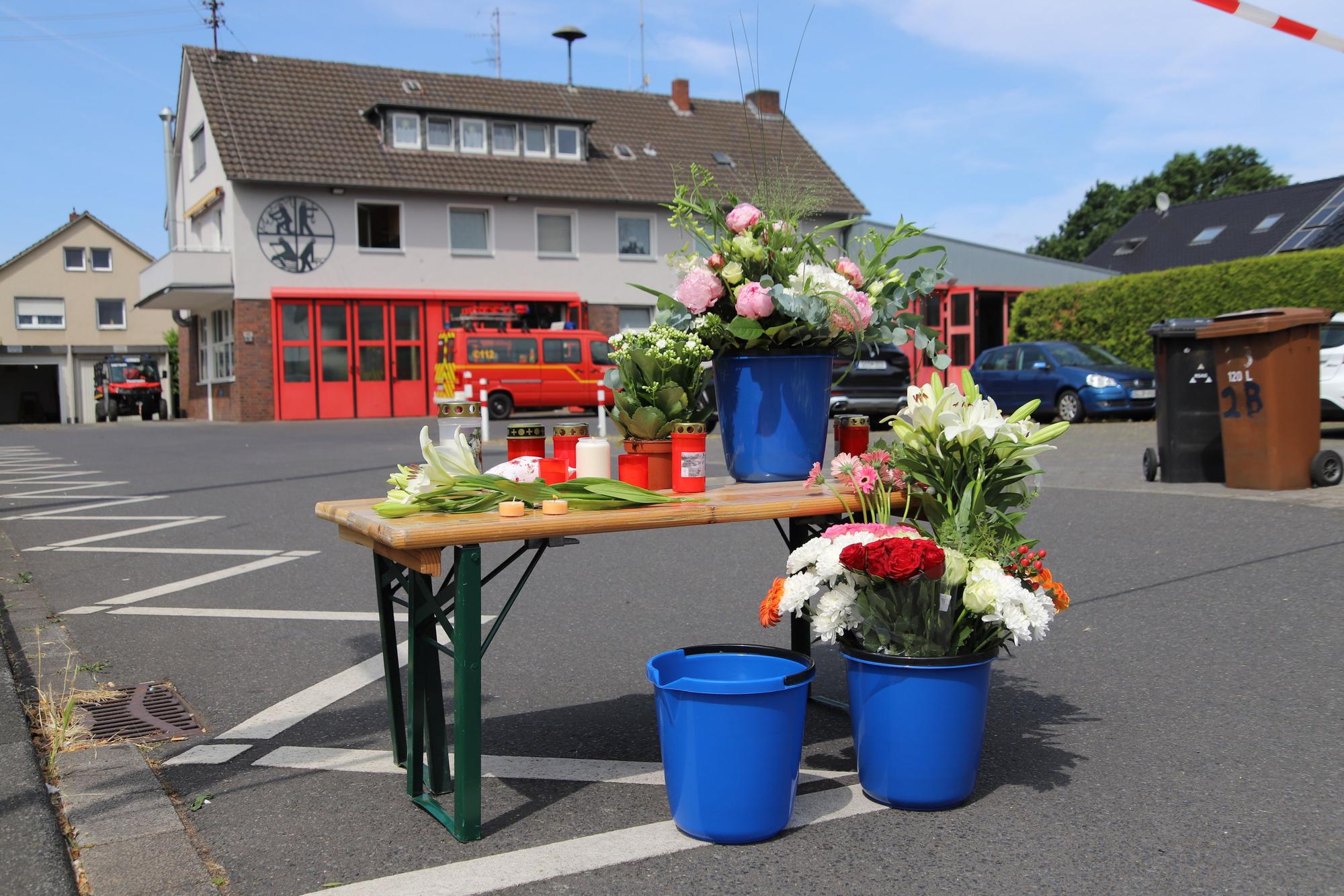 Trauerkerzen und Blumen stehen auf einem Klapptisch vor der Feuerwache in Niederpleis.