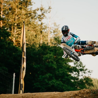 Ein Motocross-Fahrer springt mit seinem Motorrad über ein Hindernis.