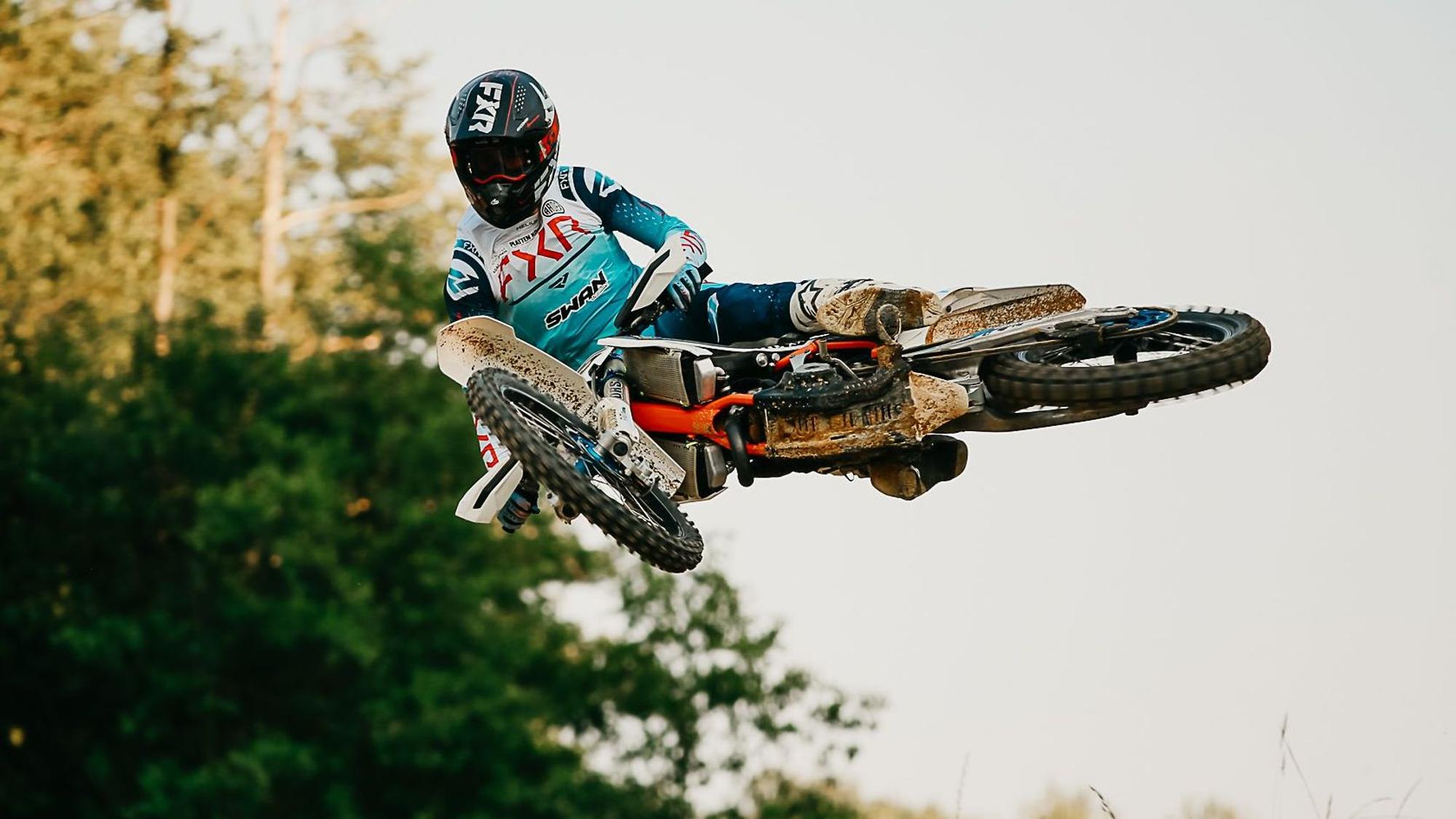 Ein Motocross-Fahrer springt mit seinem Motorrad über ein Hindernis.