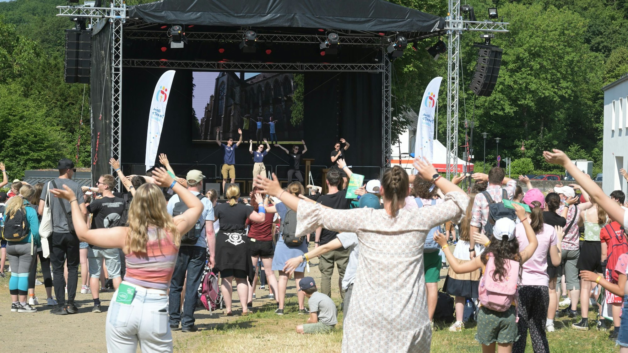 Menschen bewegen die Arme in der Luft vor einer Bühne.