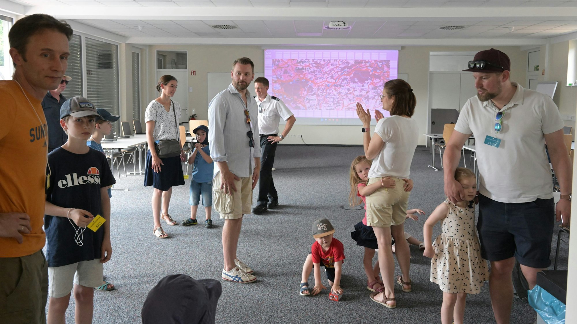 Menschenstehen in einem Raum, an dessen Stirnseite eine Karte an die Wand projiziert ist.