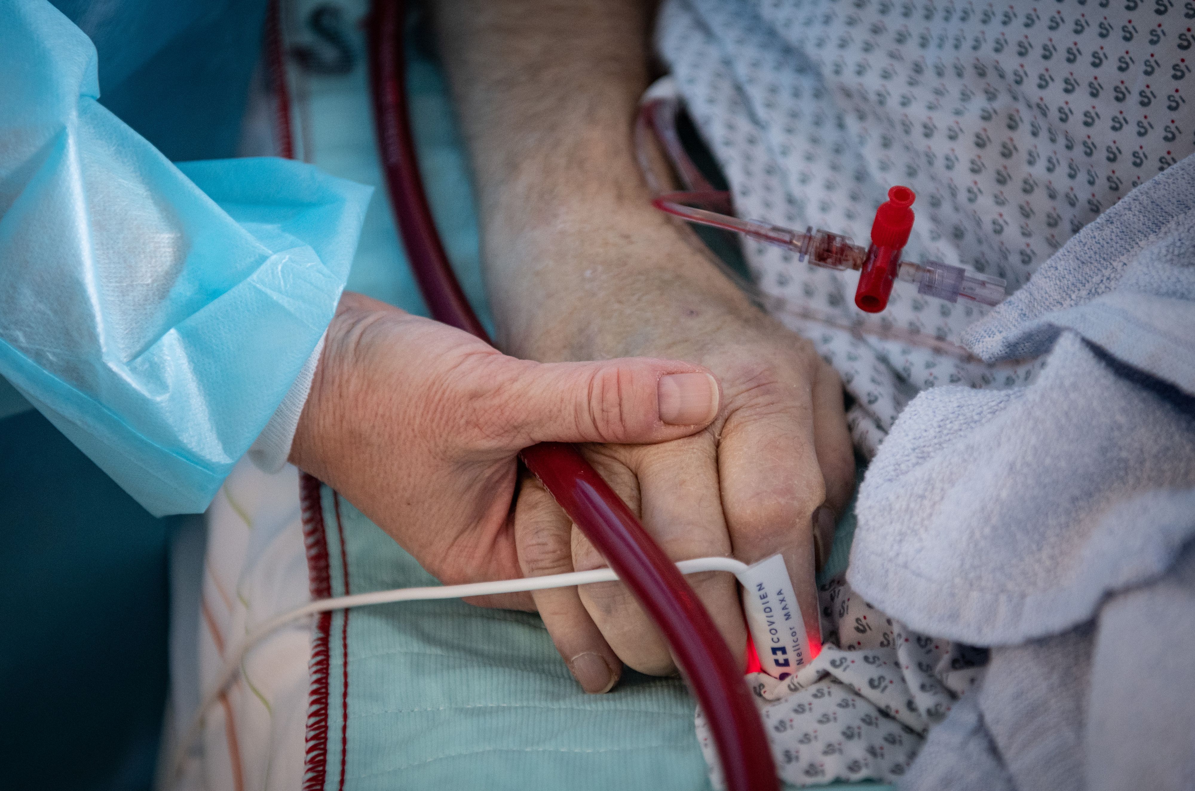 Eine Krankenschwester versorgt einen schwer an Corona erkrankten Patienten auf der Intensivstation des Klinikums in Fulda und hält dabei die Hand des Mannes. (Symbolfoto)
