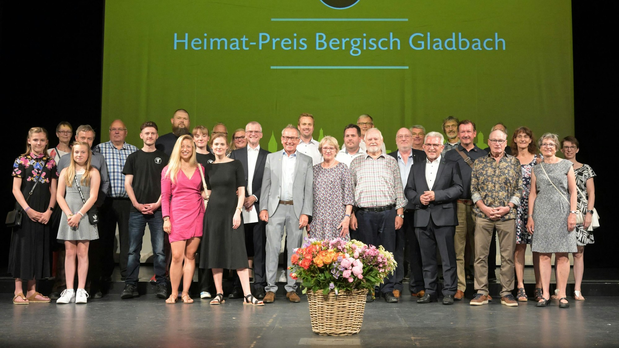 Menschen stehen zum Gruppenbild auf einer Bühne, an deren Rückseite der Schriftzug Heimat-Preis Bergisch Gladbach prangt.
