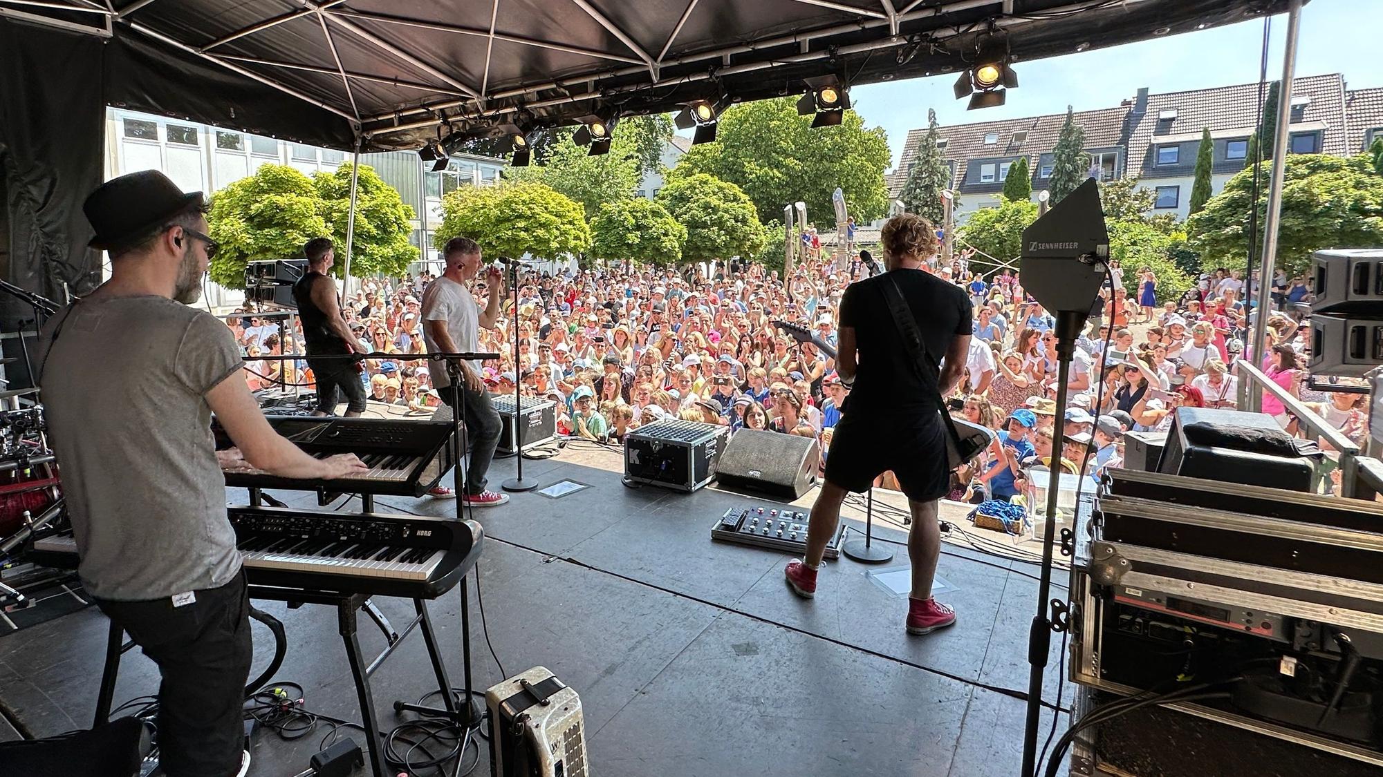Die Band Kasalla spielt vor den Grundschülern auf der Bühne.