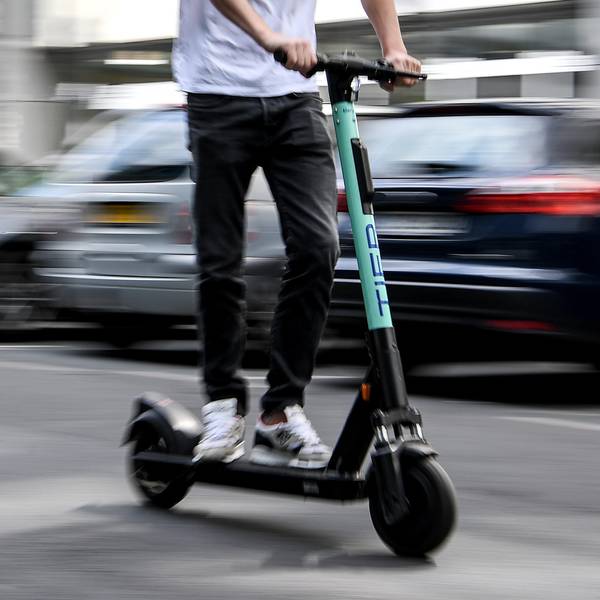 Ein Mann fährt mit einem E-Tretroller auf der Straße.