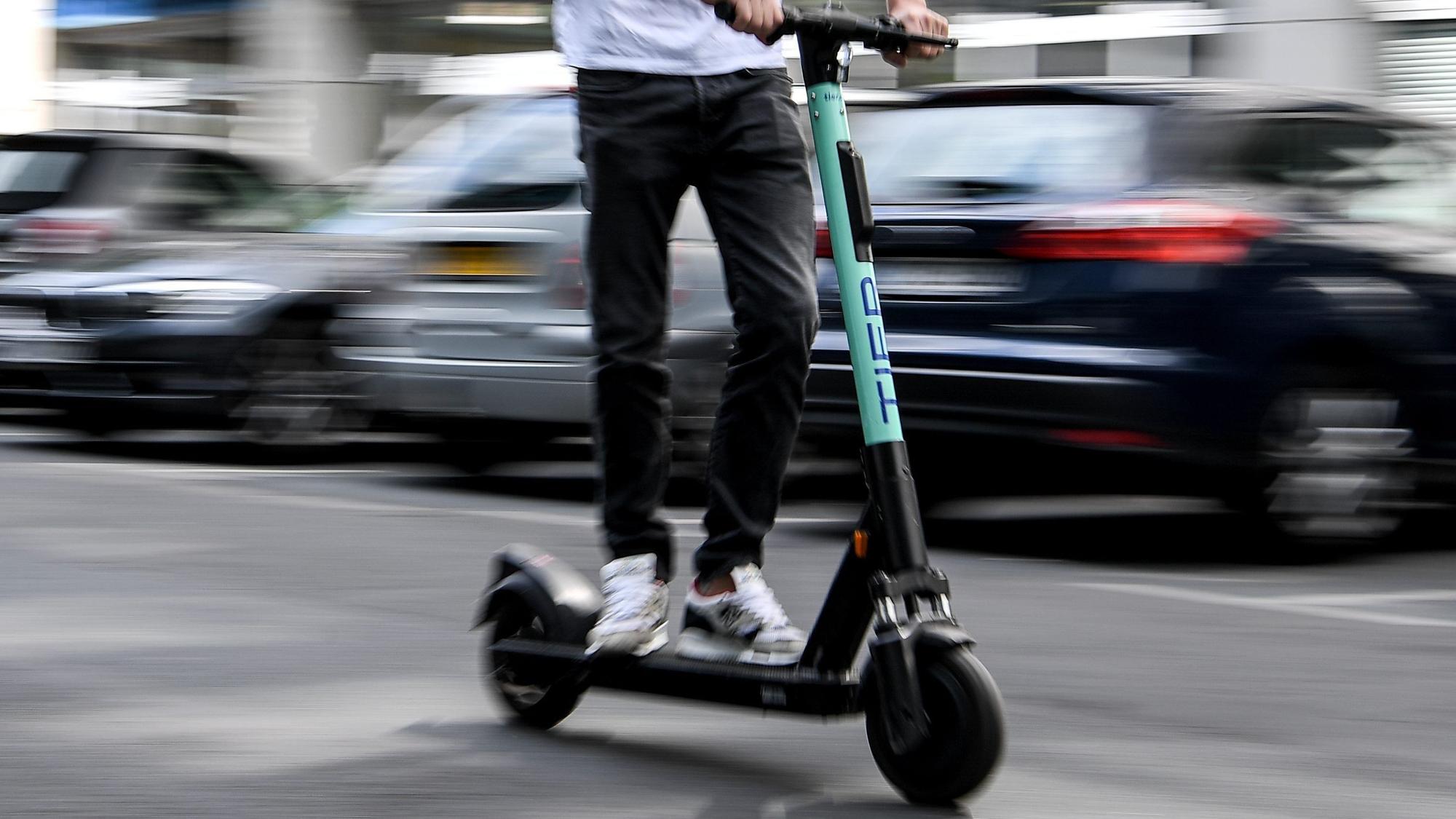 Ein Mann fährt mit einem E-Scooter auf der Straße.