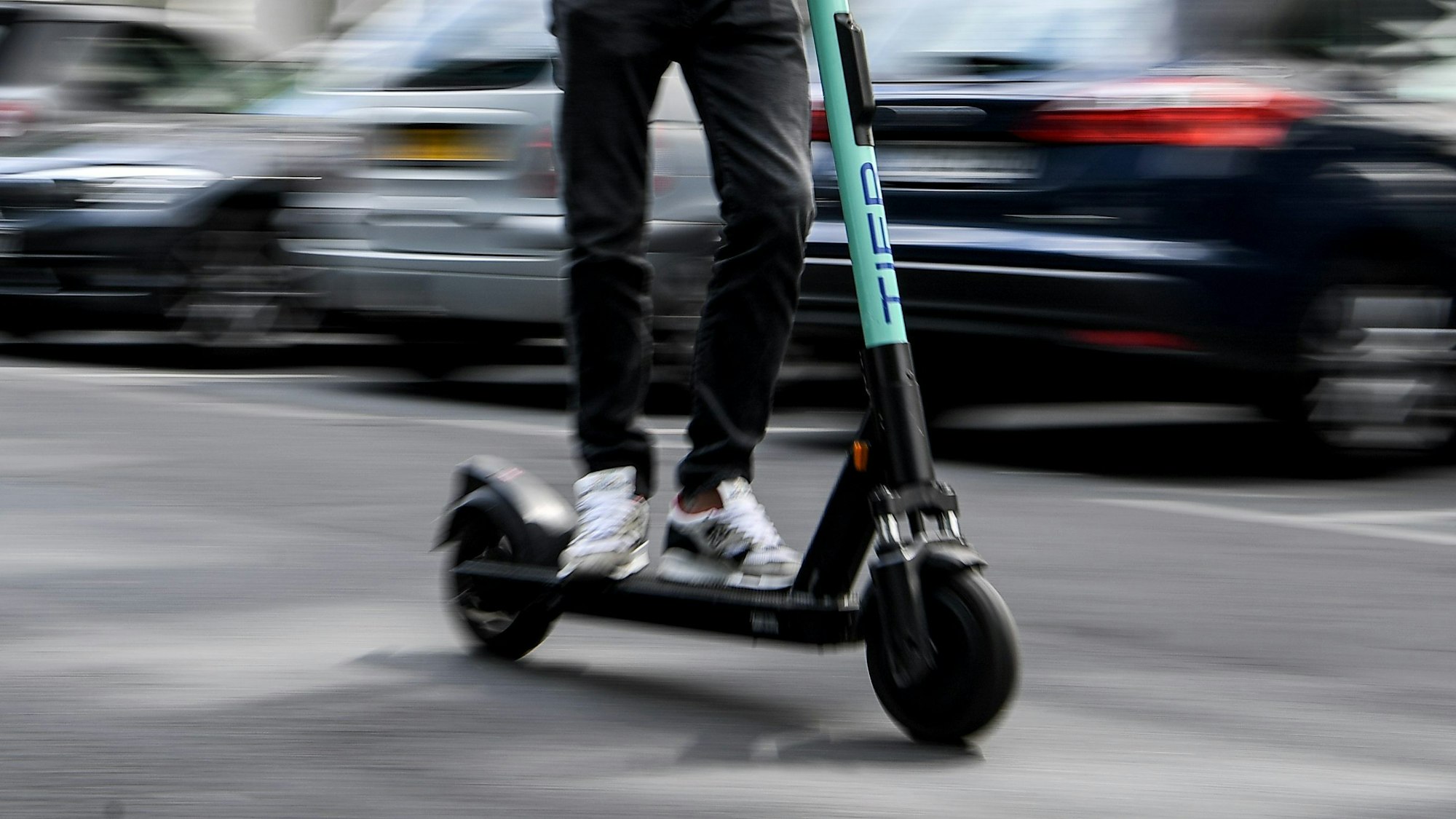 Ein Mann fährt mit einem E-Tretroller auf der Straße.