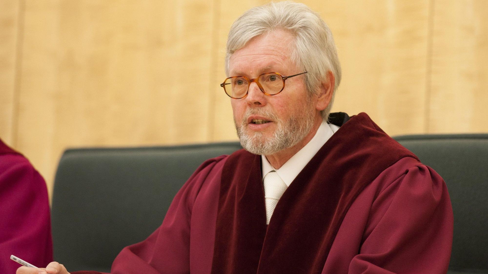 Der ehemalige Präsident des Verfassungsgerichtshofs, Michael Bertrams, schaut in die Ferne. Er trägt eine rote Richterrobe.